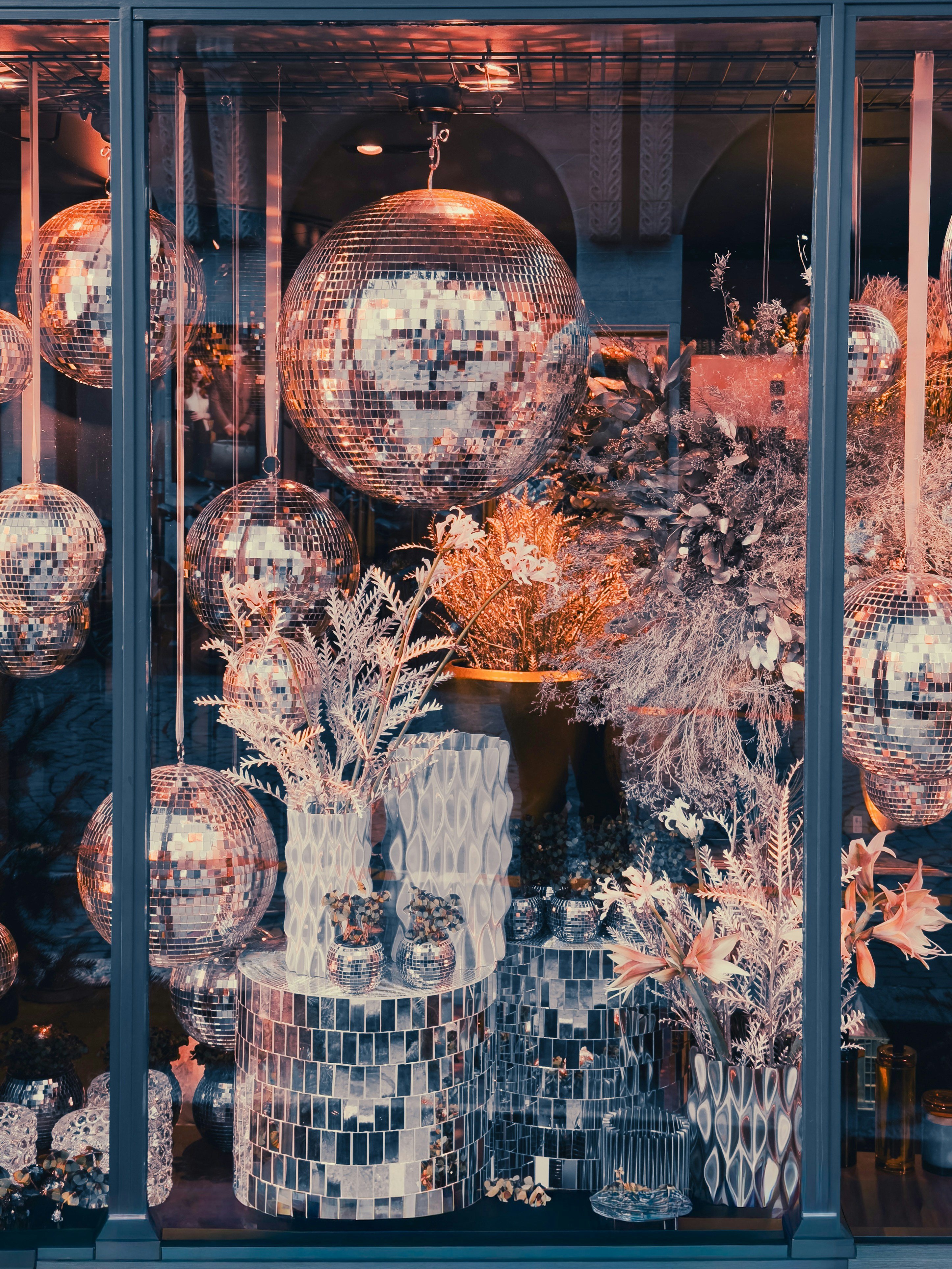 店のショーウィンドウに映るディスコボールと装飾植物