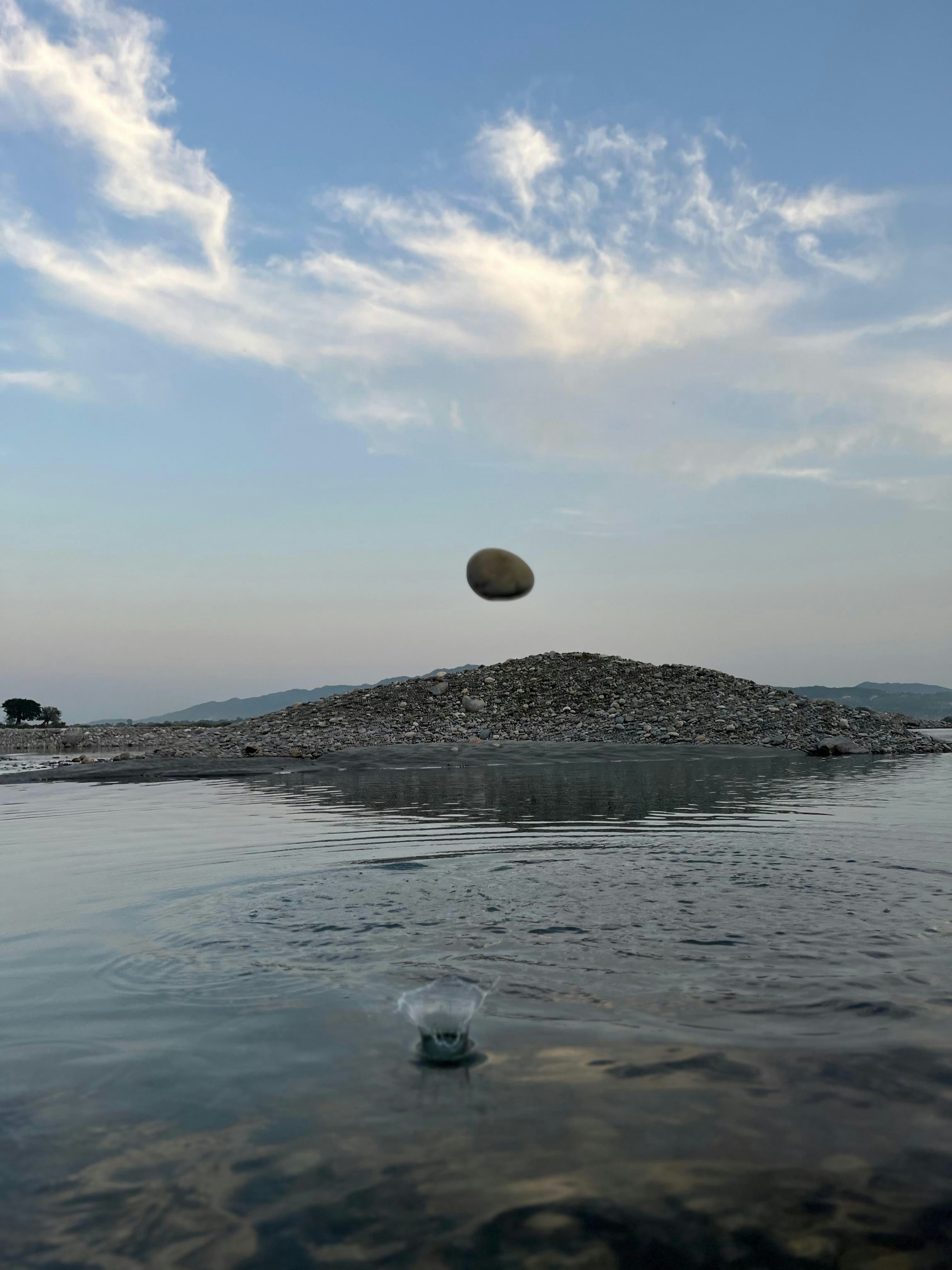 Una pietra è a mezz'aria sopra l'acqua che schizza.
