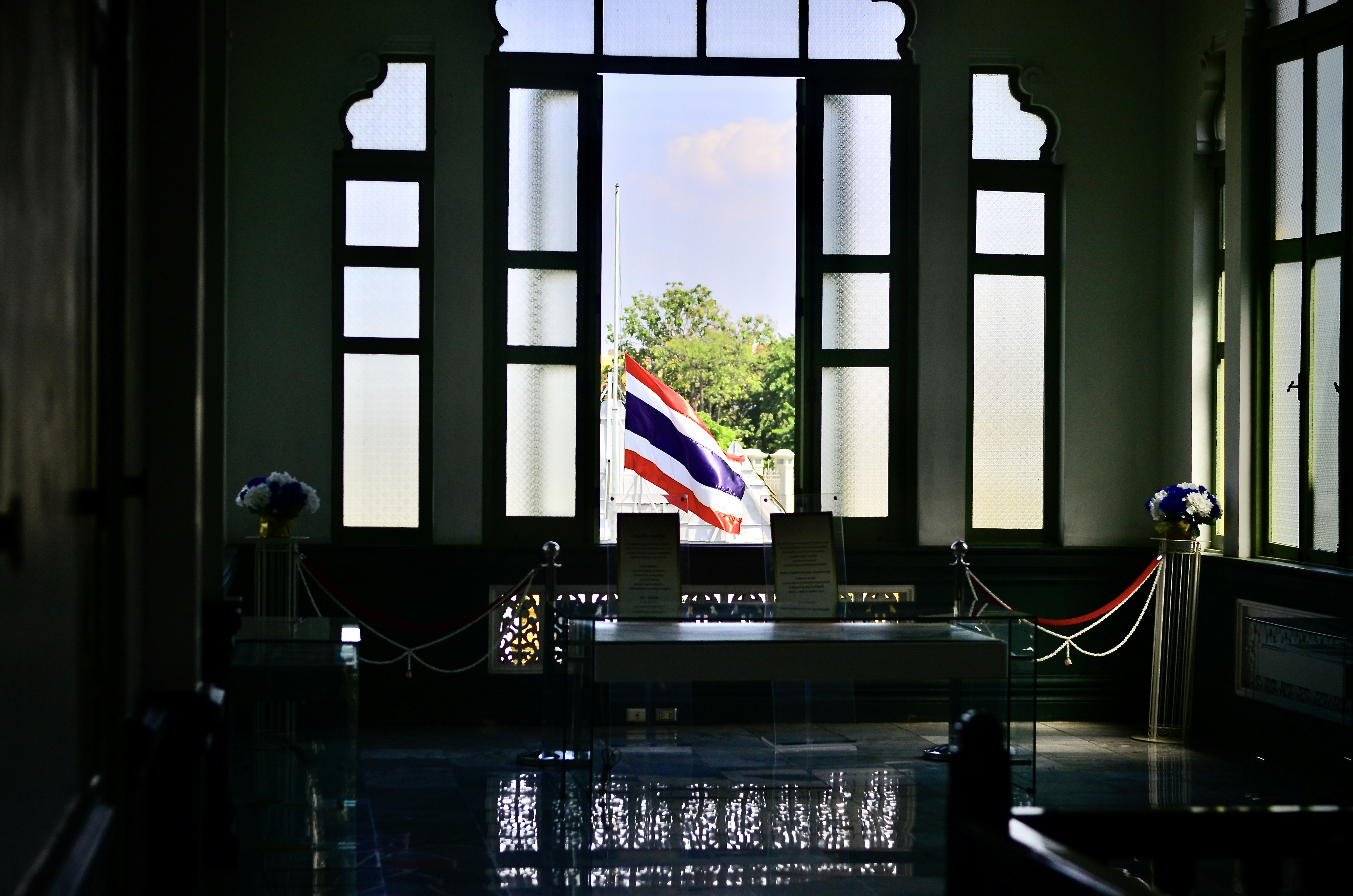 Thai flag waving outside a window with ornate frame