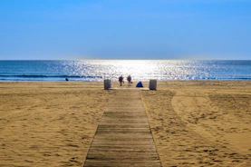 Wooden path leads to people on a sunny beach