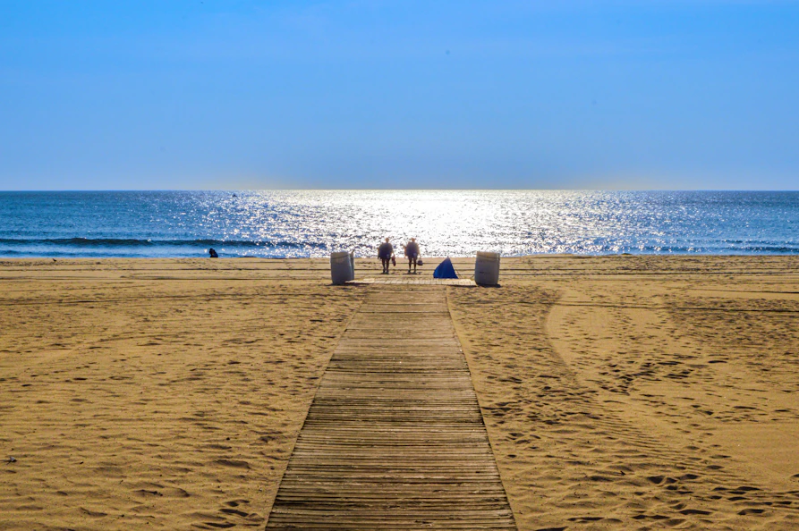 Wooden path leads to people on a sunny beach