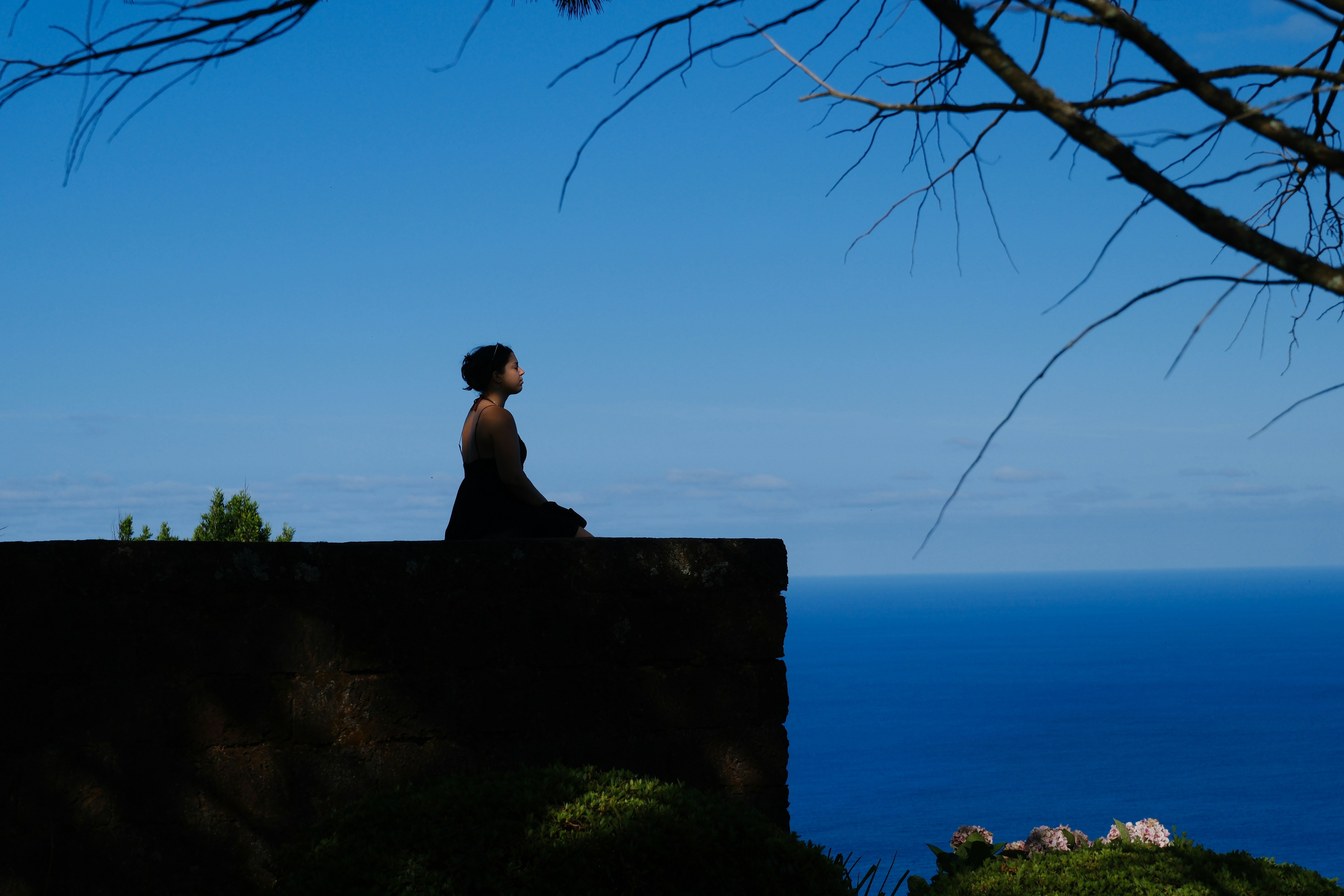 Woman meditating on cliff overlooking blue ocean