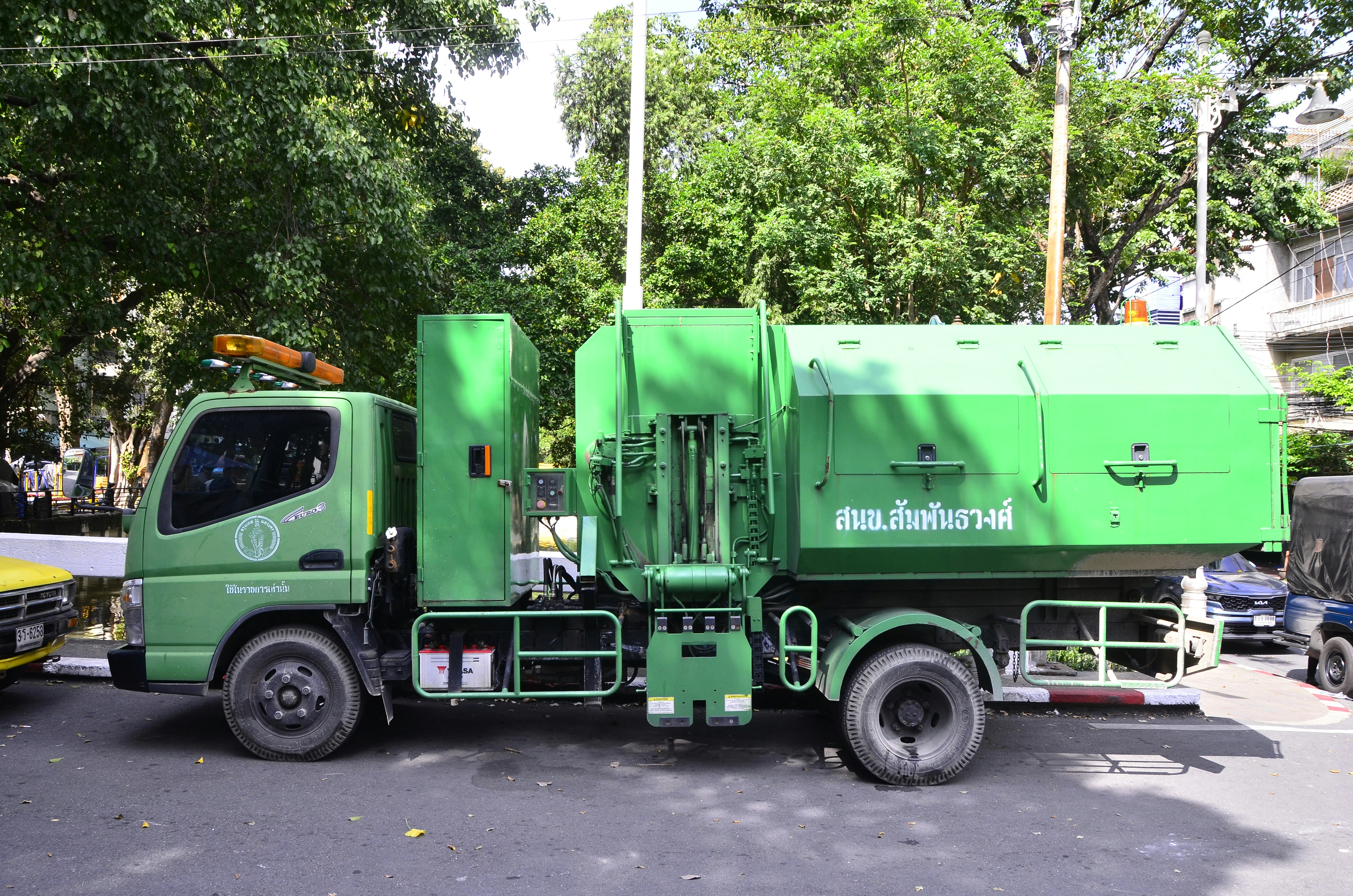 A green garbage truck parked on the street.