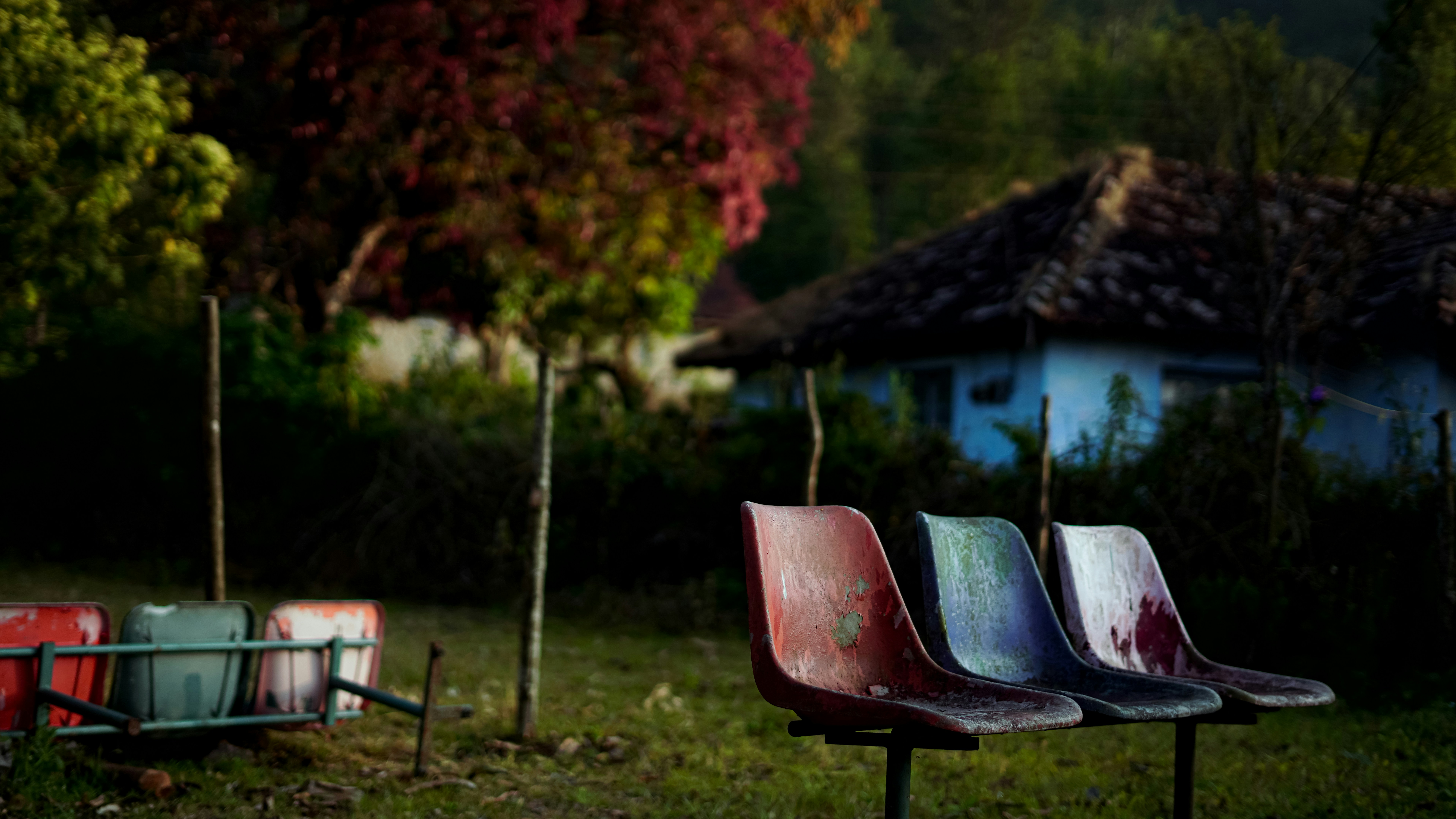 Three empty chairs in front of a rural house