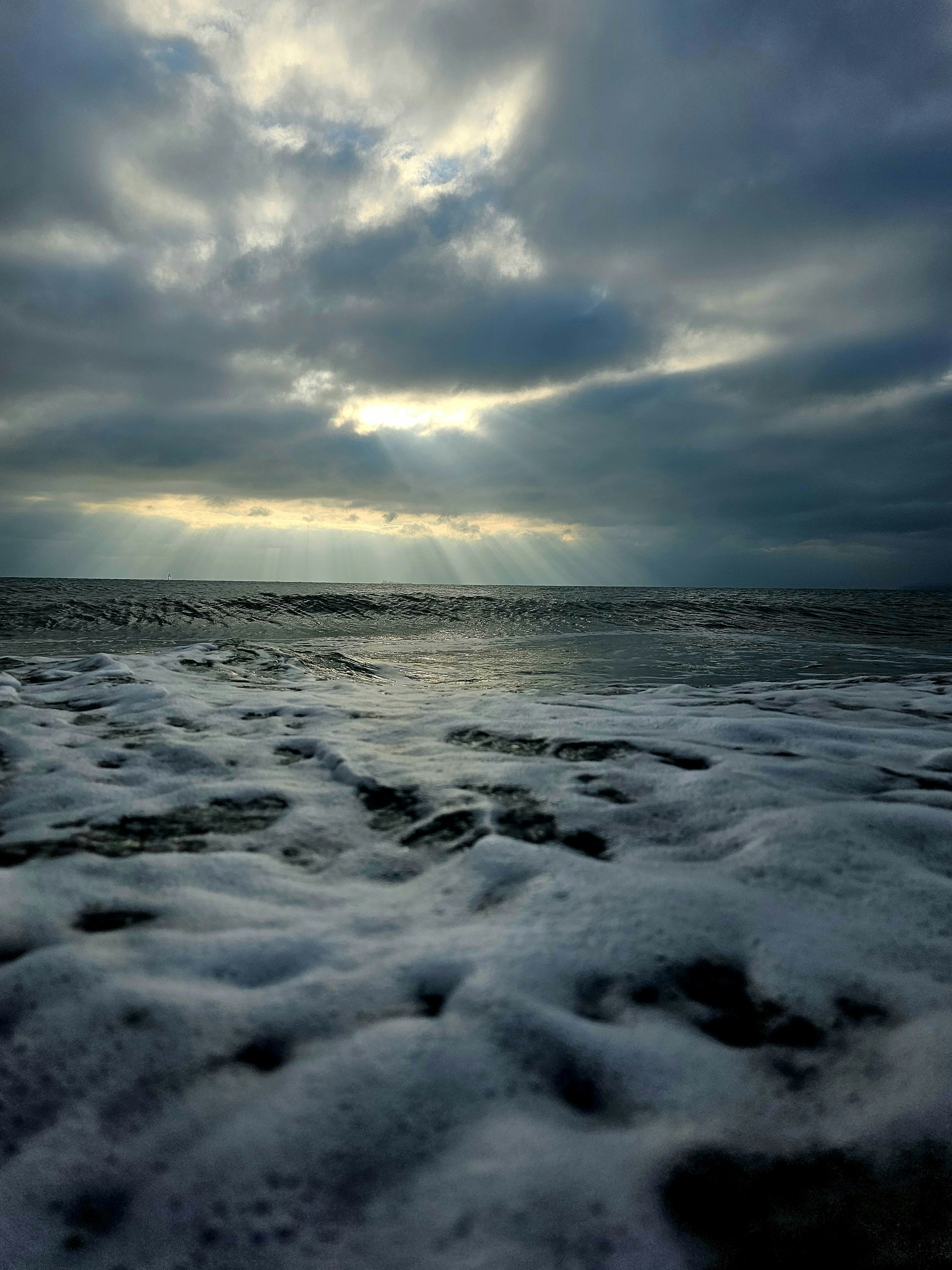 Sunbeams break through stormy clouds over the ocean.
