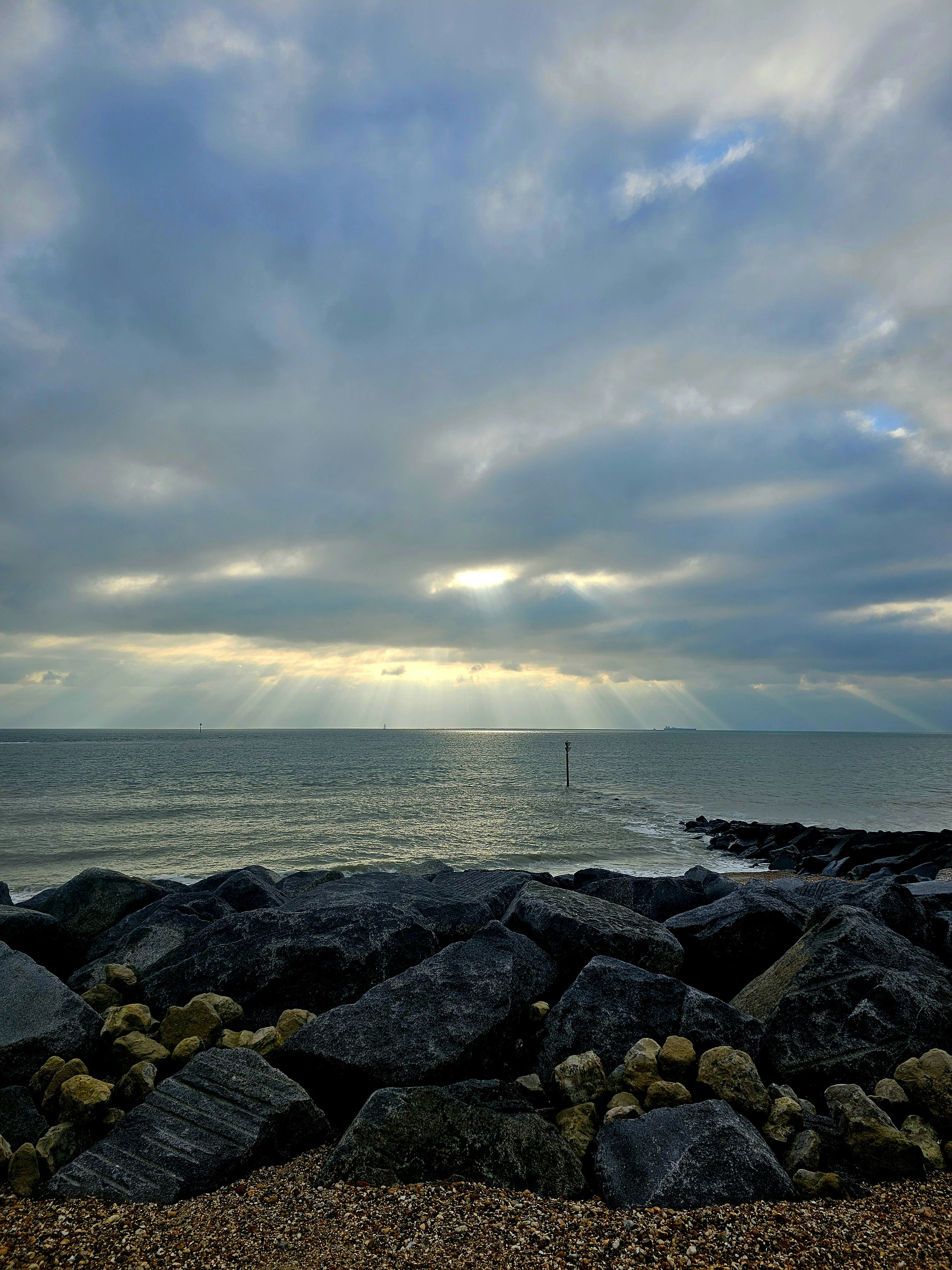 Sunbeams break through dramatic clouds over the ocean.