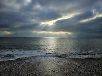 Sunbeams break through dramatic clouds over the ocean.