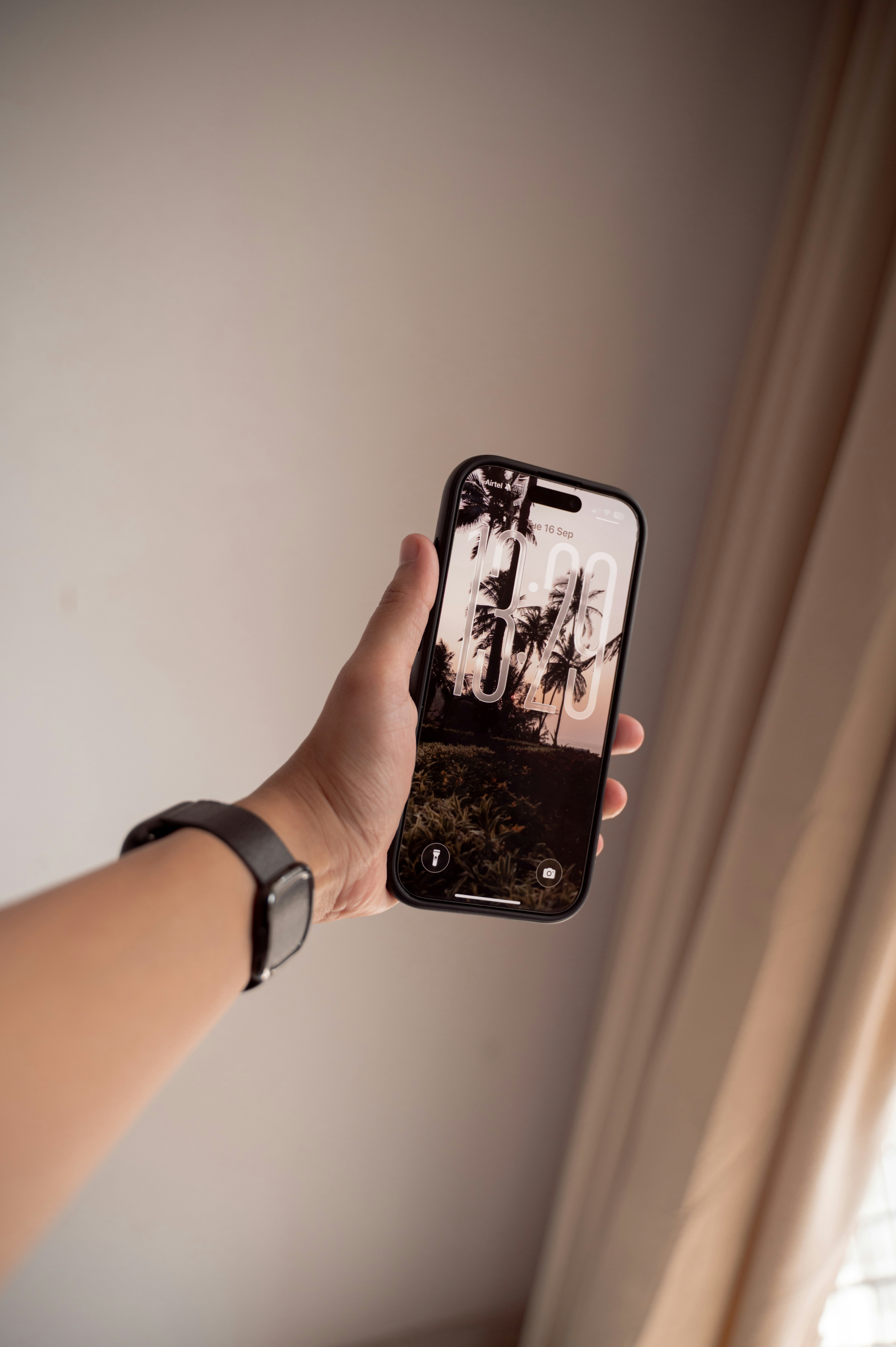 Hand holding a smartphone with a scenic wallpaper.