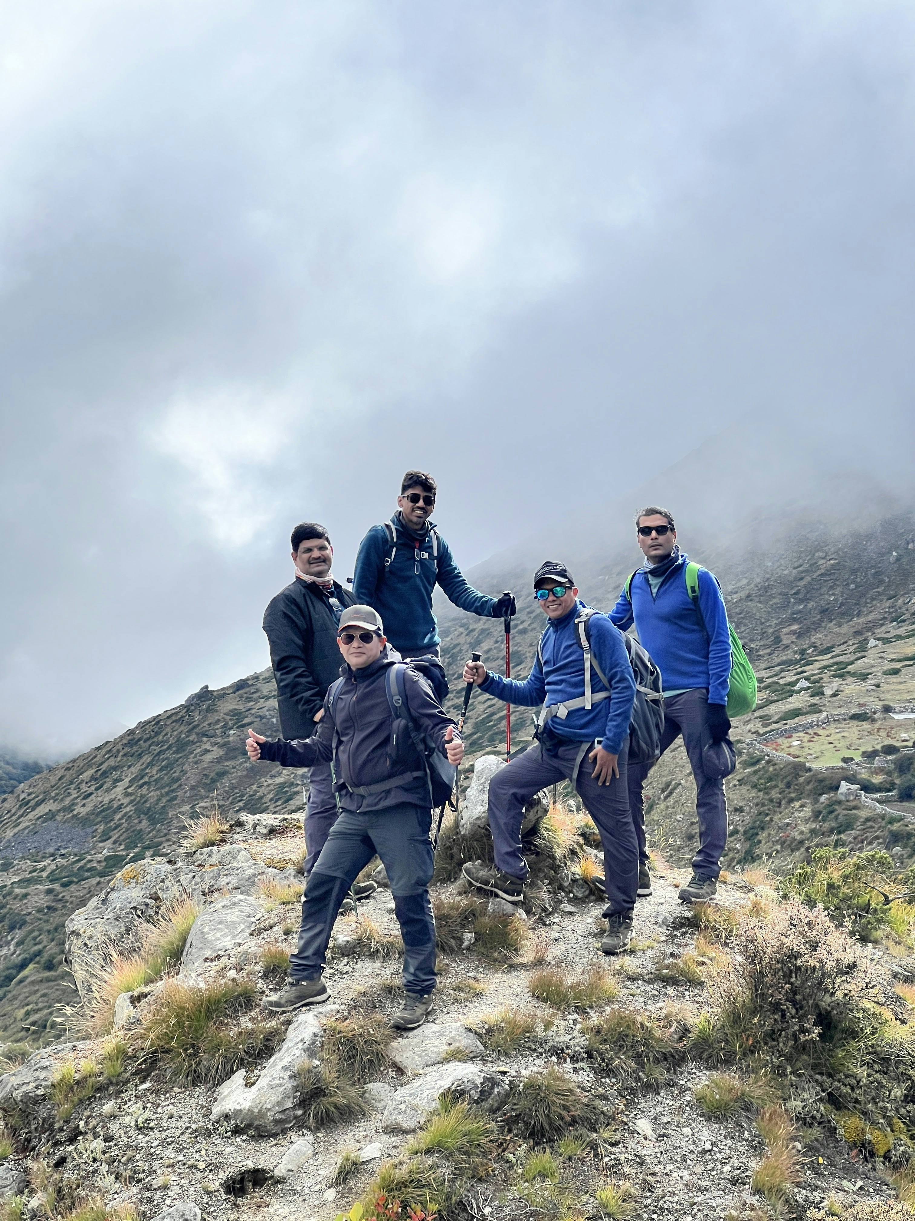 Five hikers posing on a rocky mountain trail.