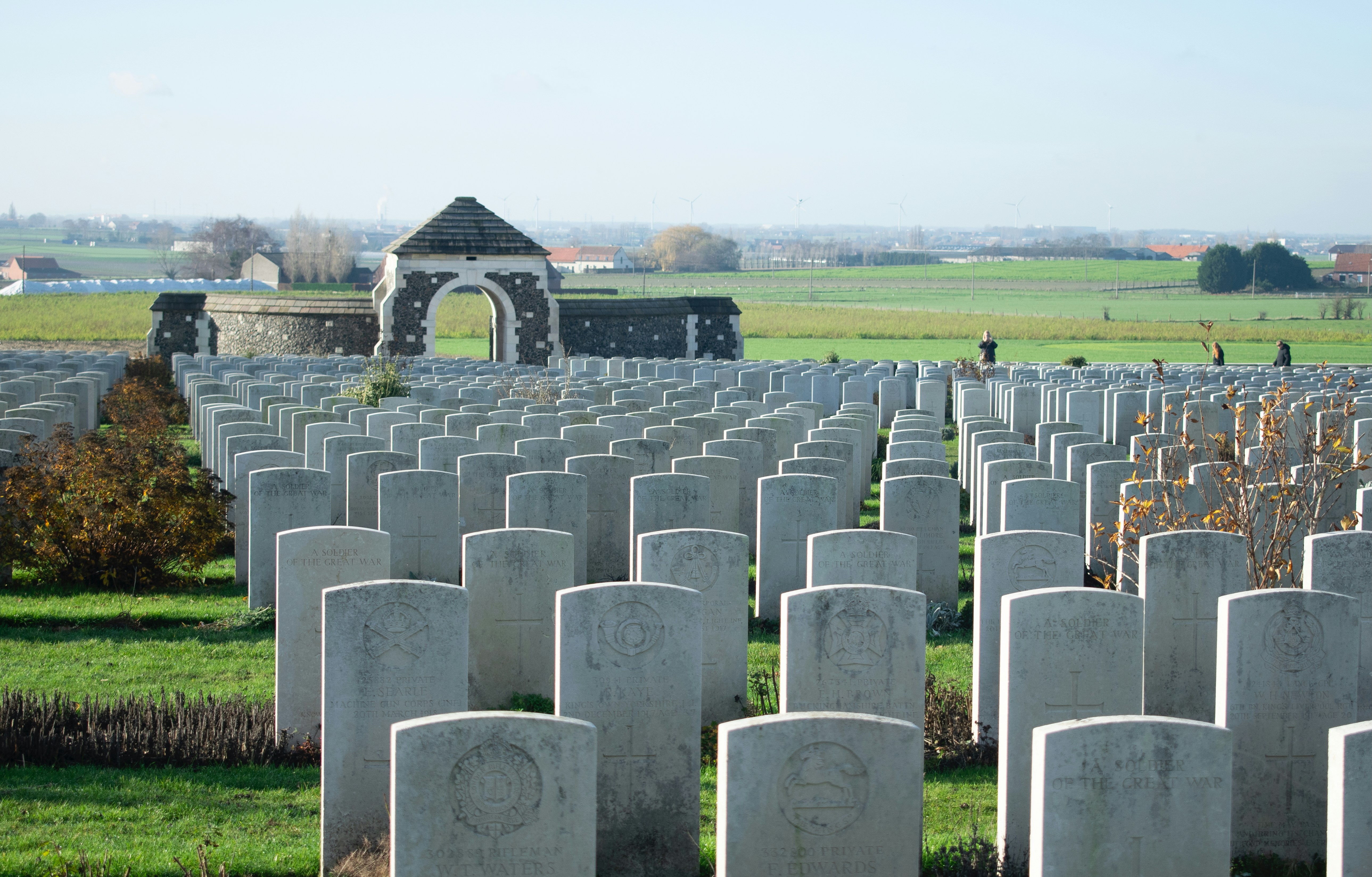 Rows of white headstones in a cemetery with archway.
