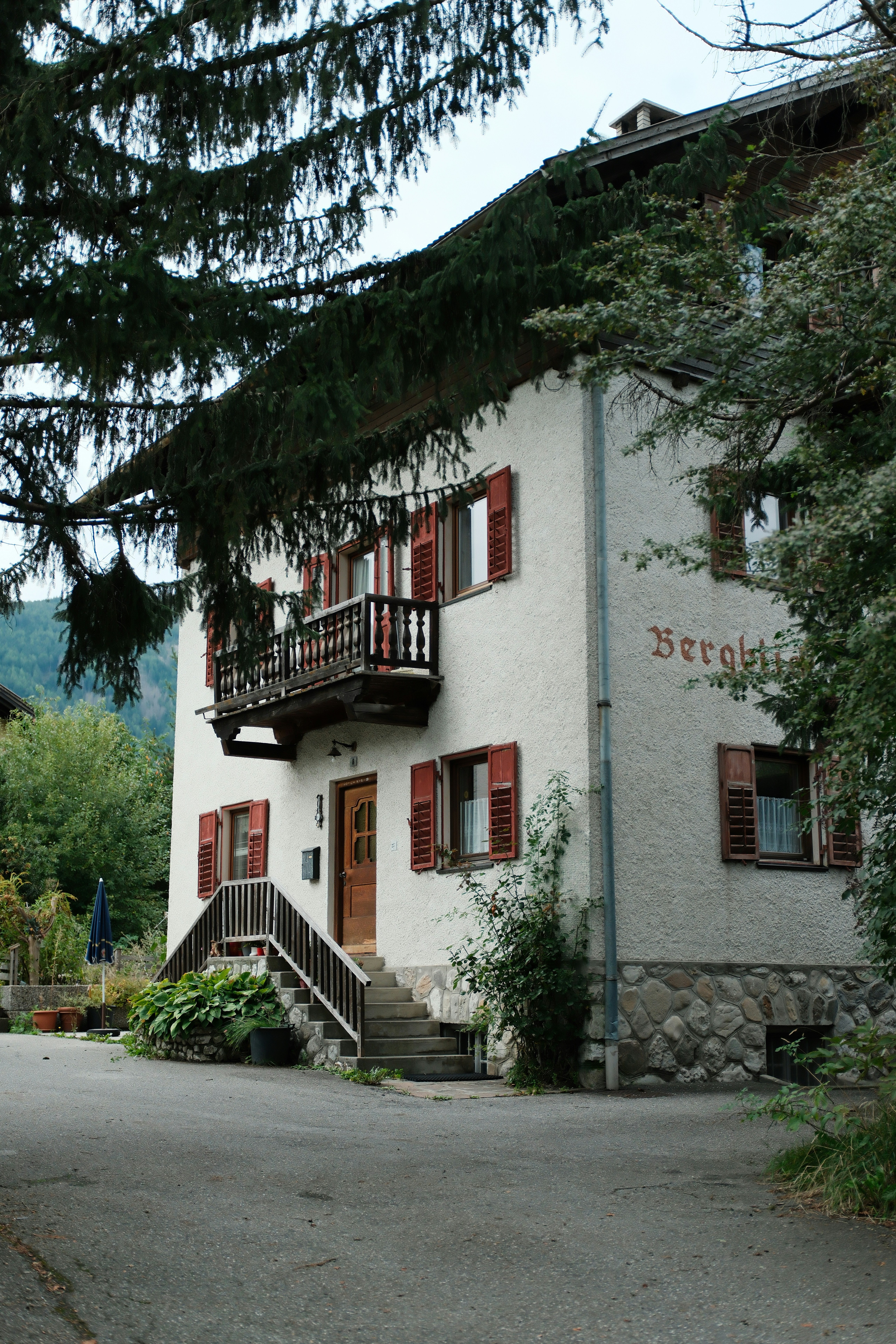 Un edificio bianco con persiane rosse e un balcone.