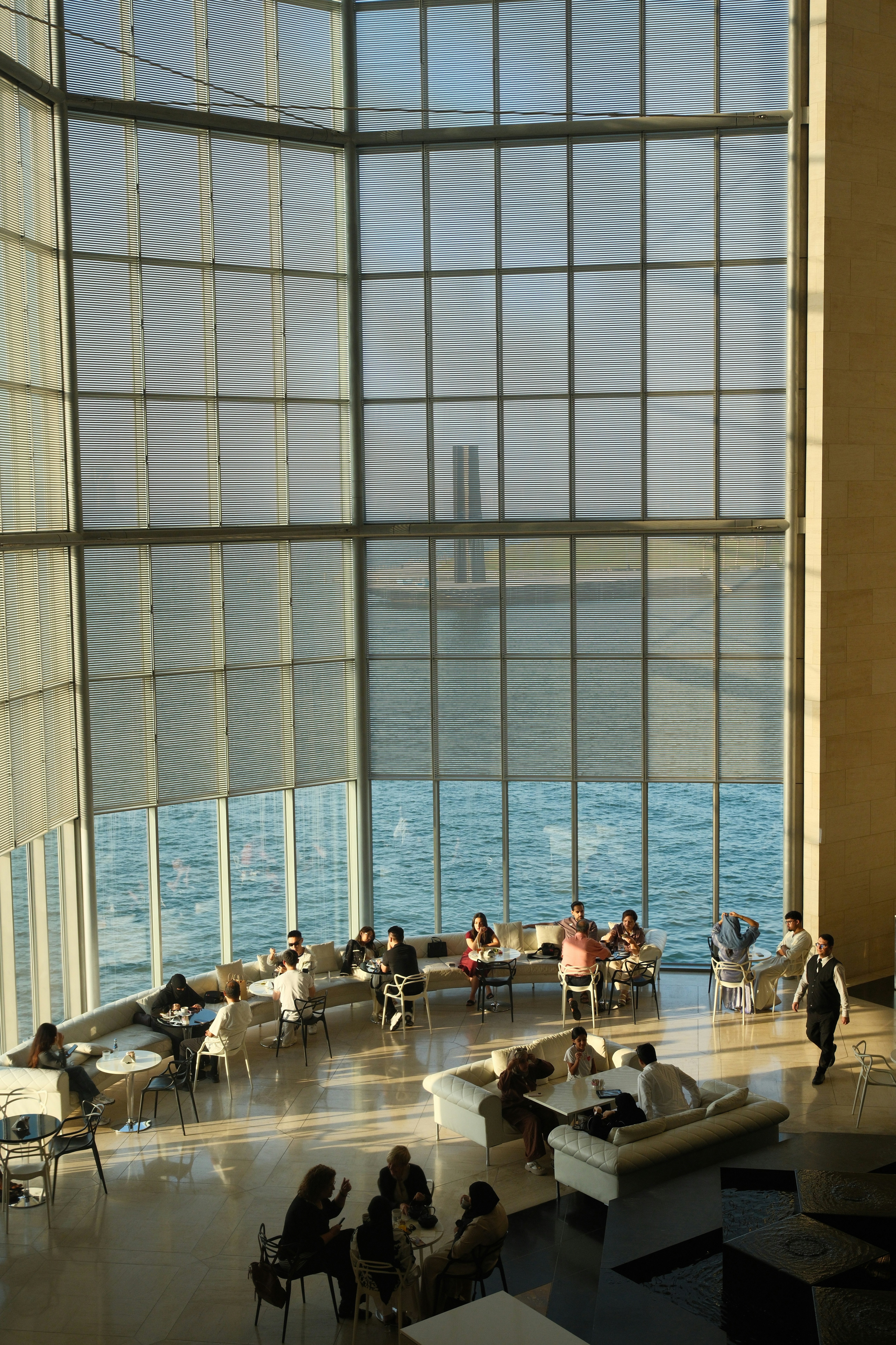 People relaxing in a sunlit atrium with ocean view