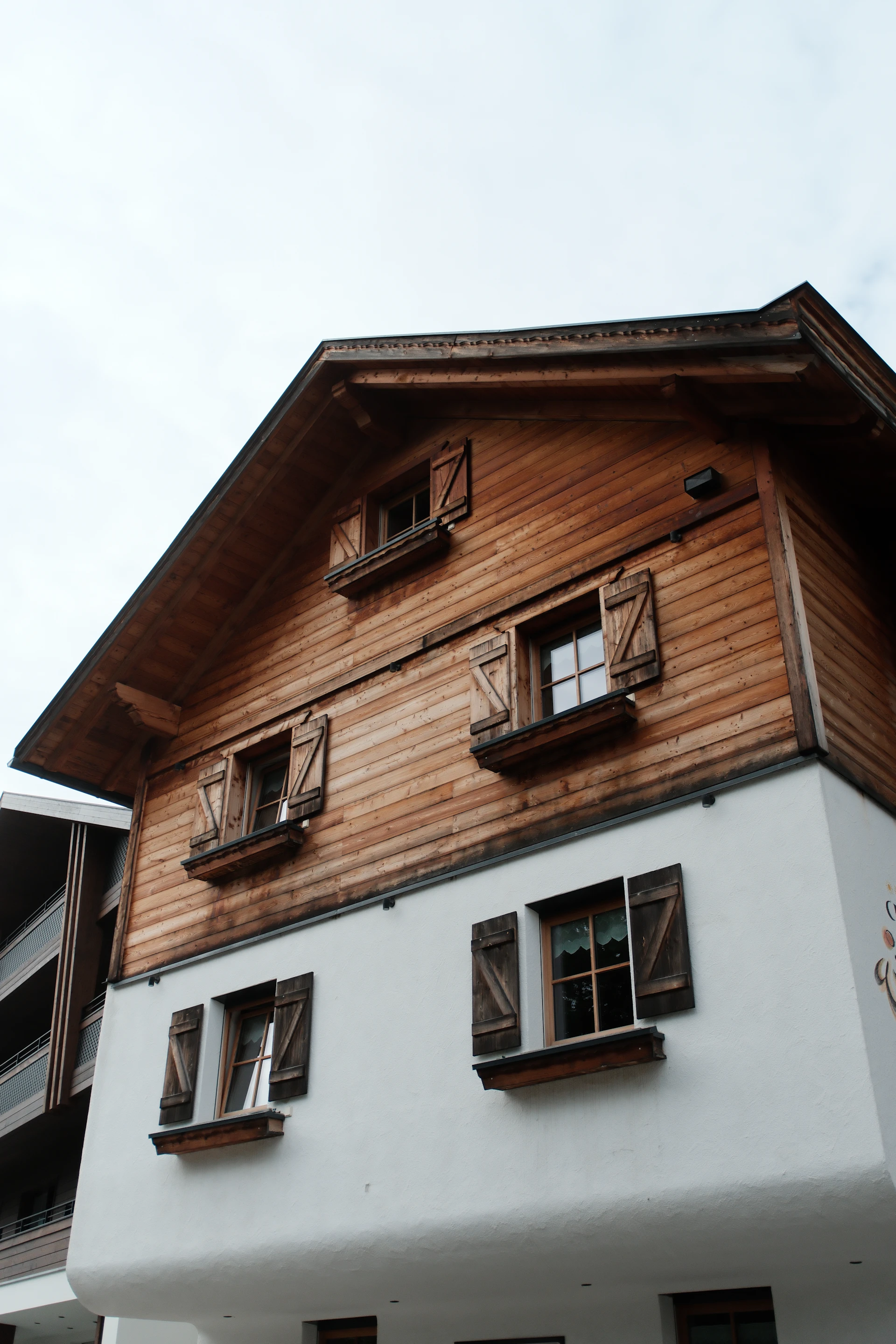 Wooden chalet with white lower level and shutters