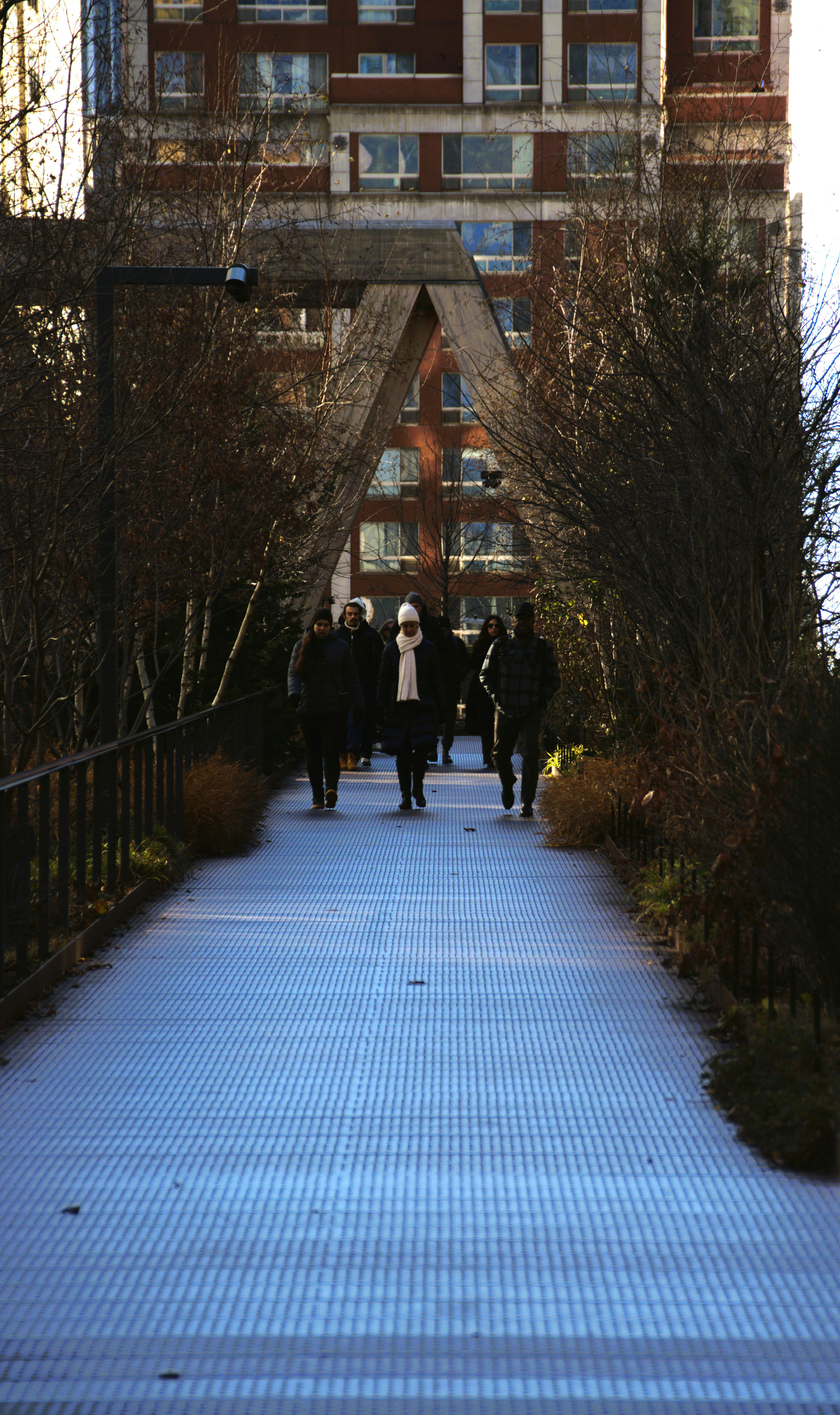 People walk on a raised walkway towards a building.