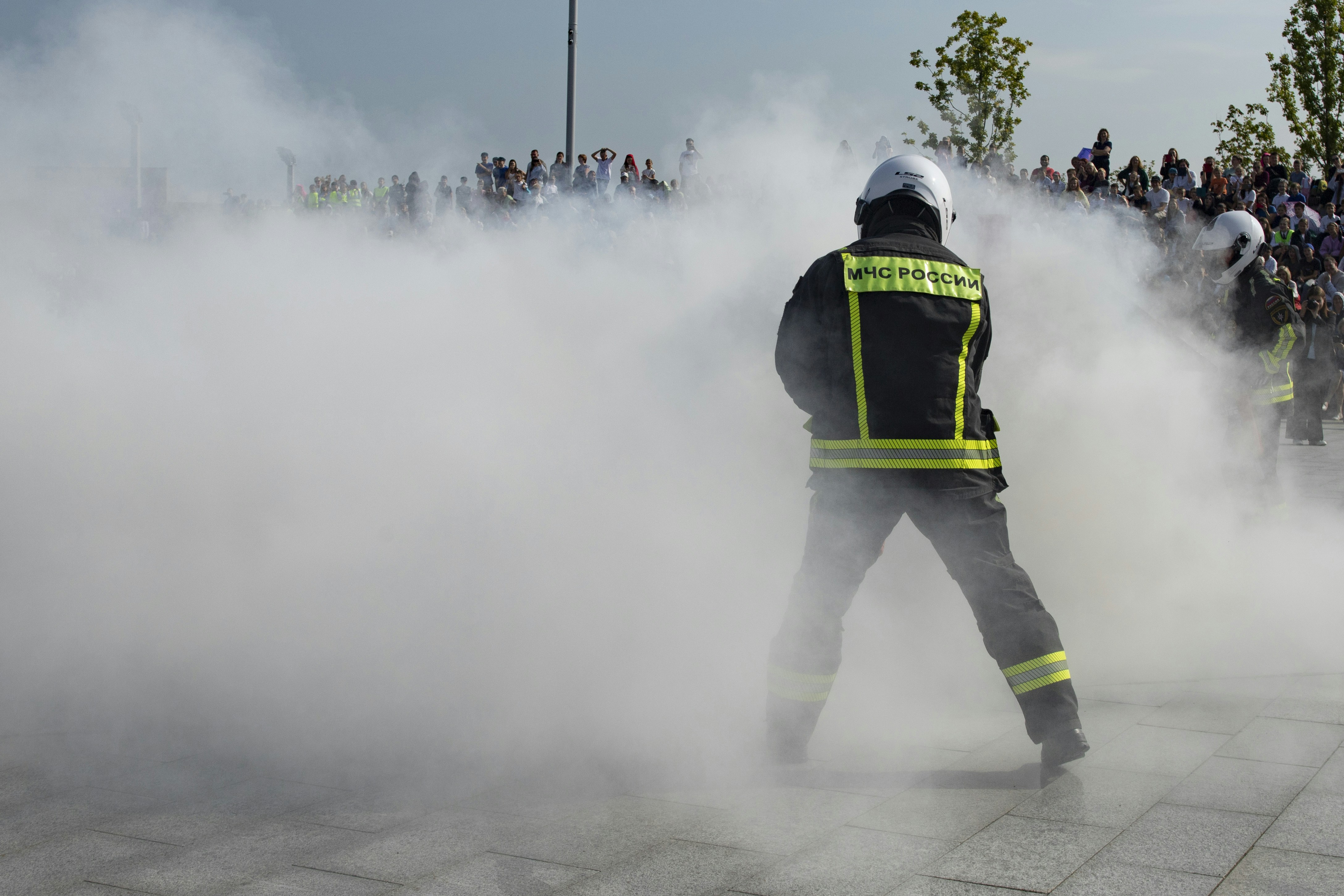 Firefighter in thick smoke with crowd in the background crowd
