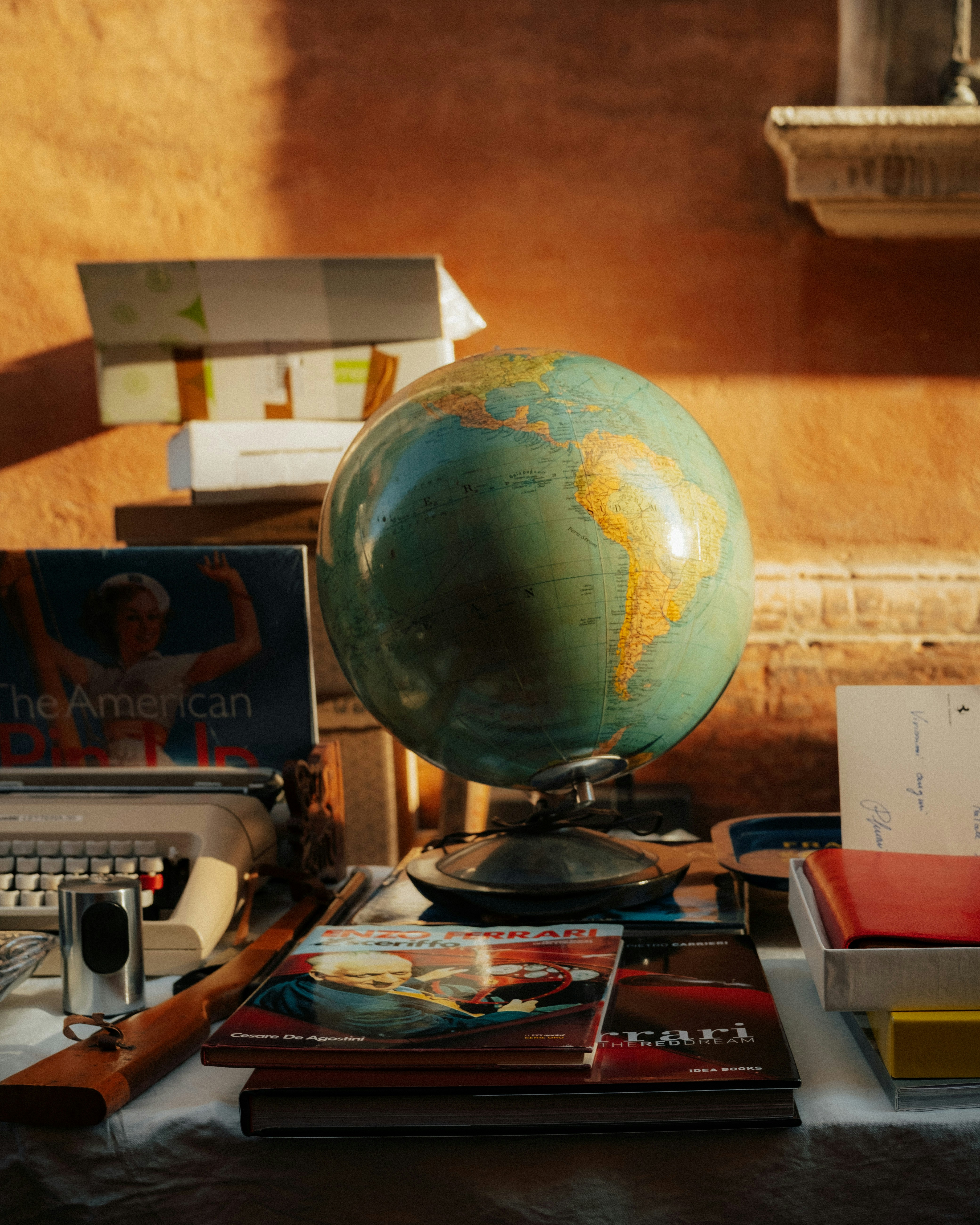 Desk with globe, books, and vintage typewriter.
