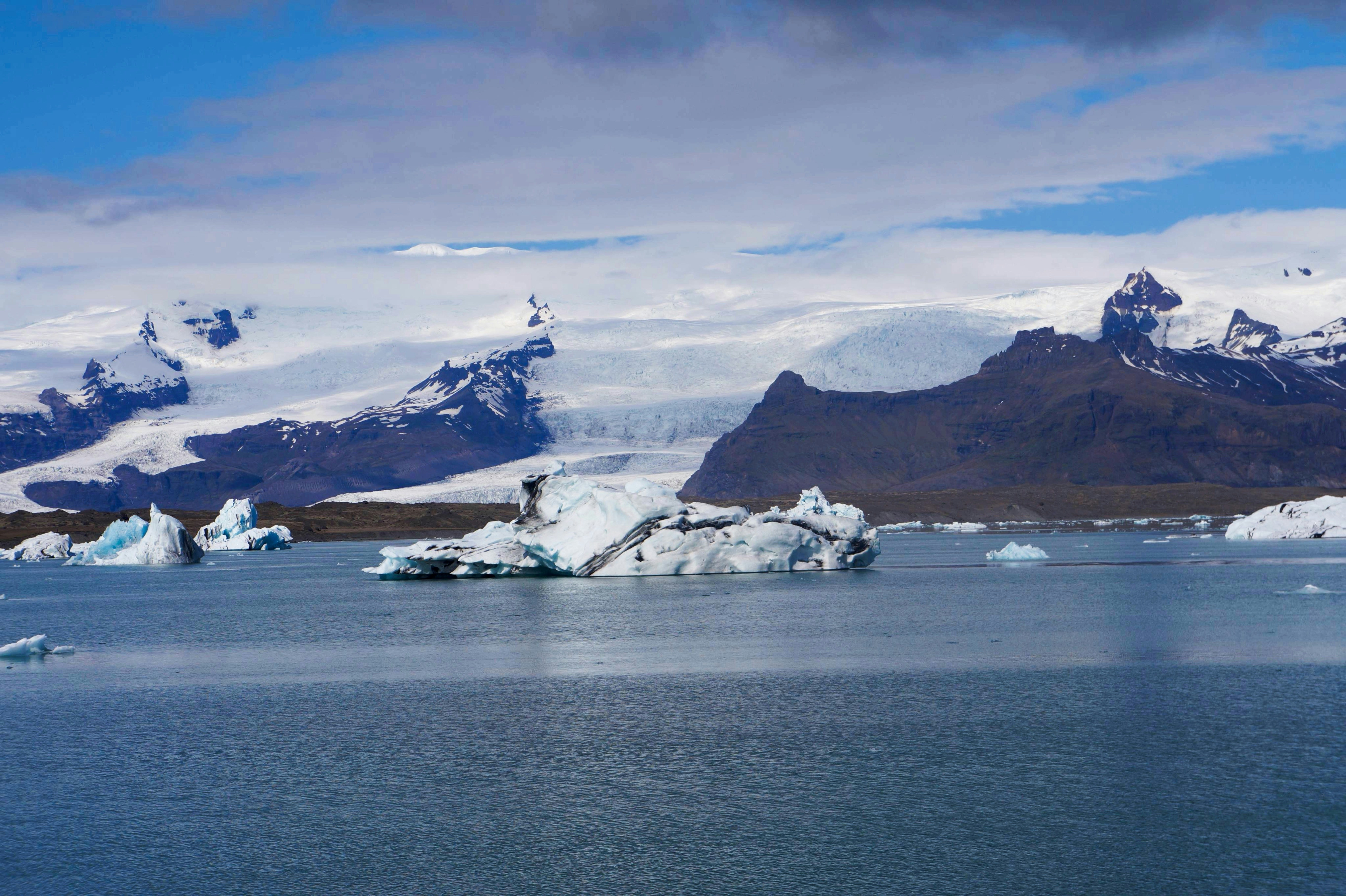 Icebergs floating in a glacial lagoon with mountains behind.