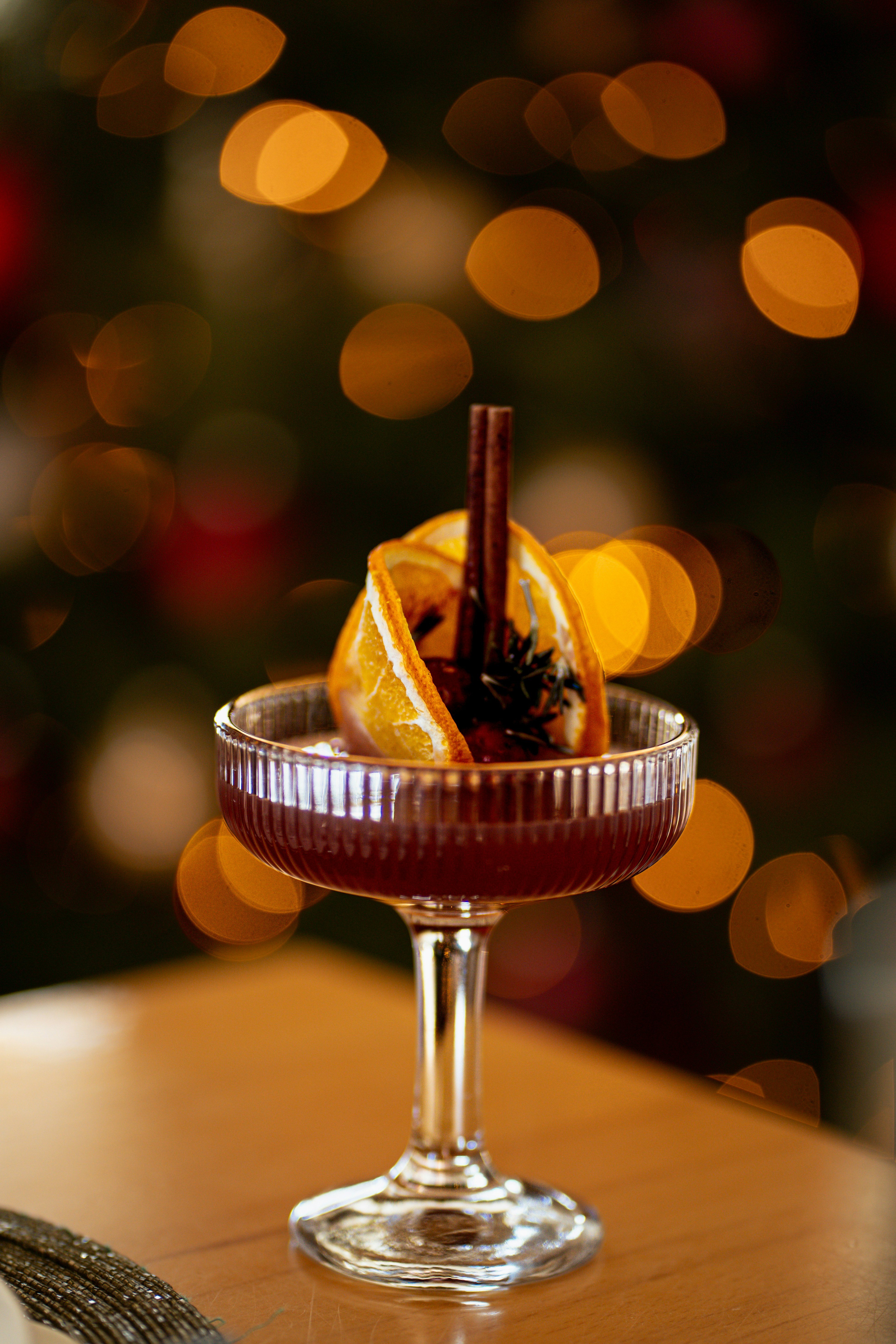 A festive cocktail garnished with orange slices and cinnamon.