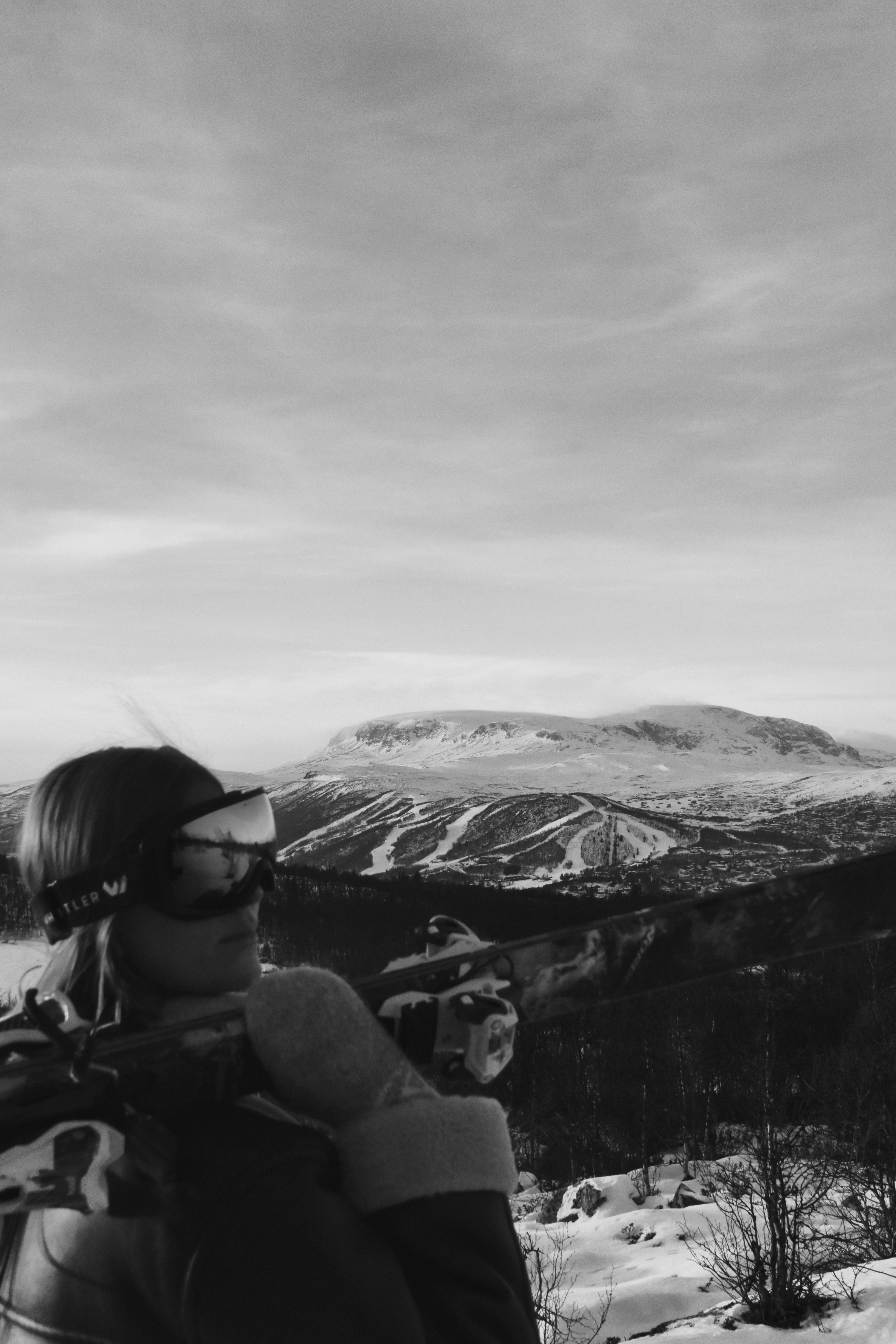 Woman in ski gear looks out at snowy mountain landscape