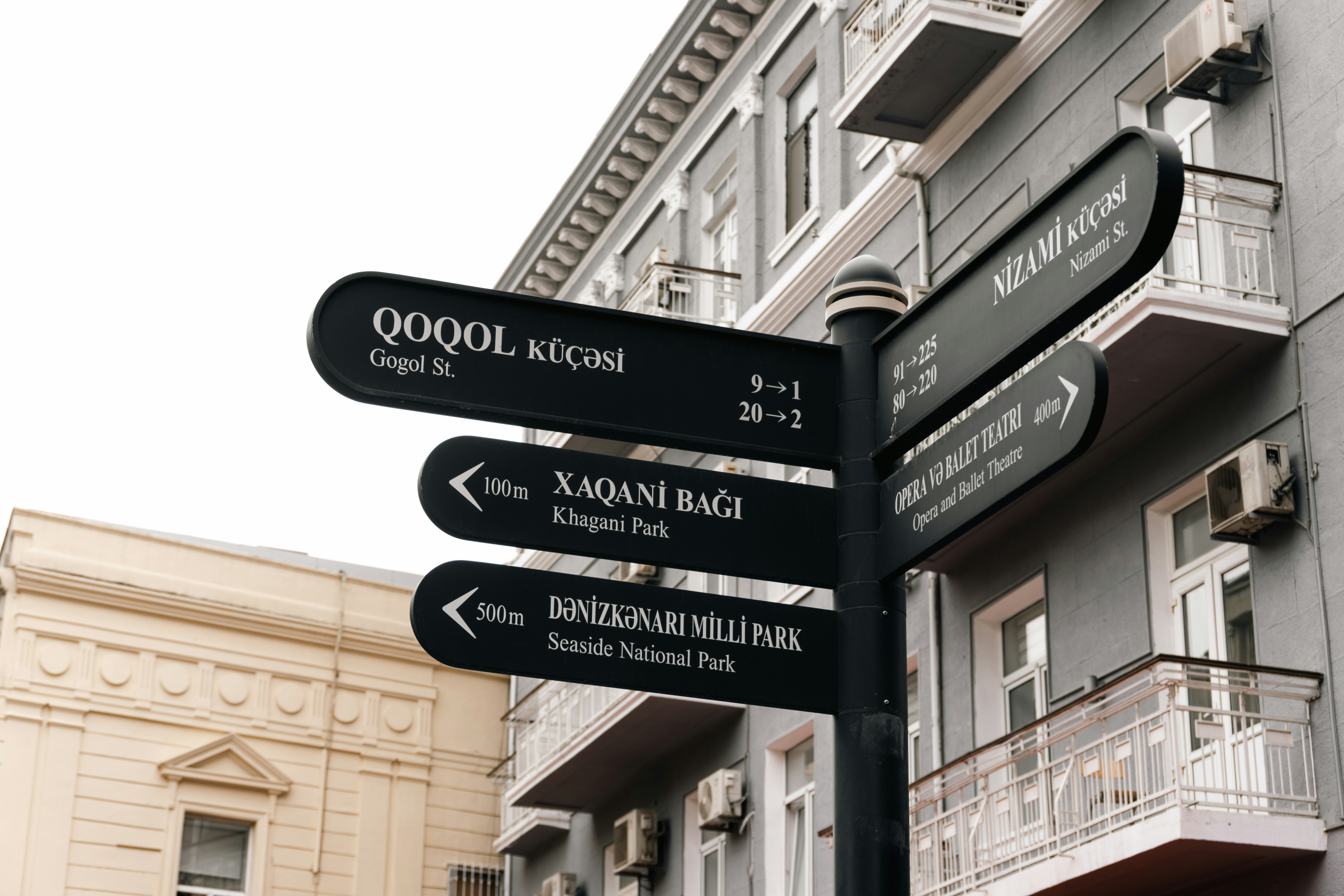Street signs point in different directions on a building.