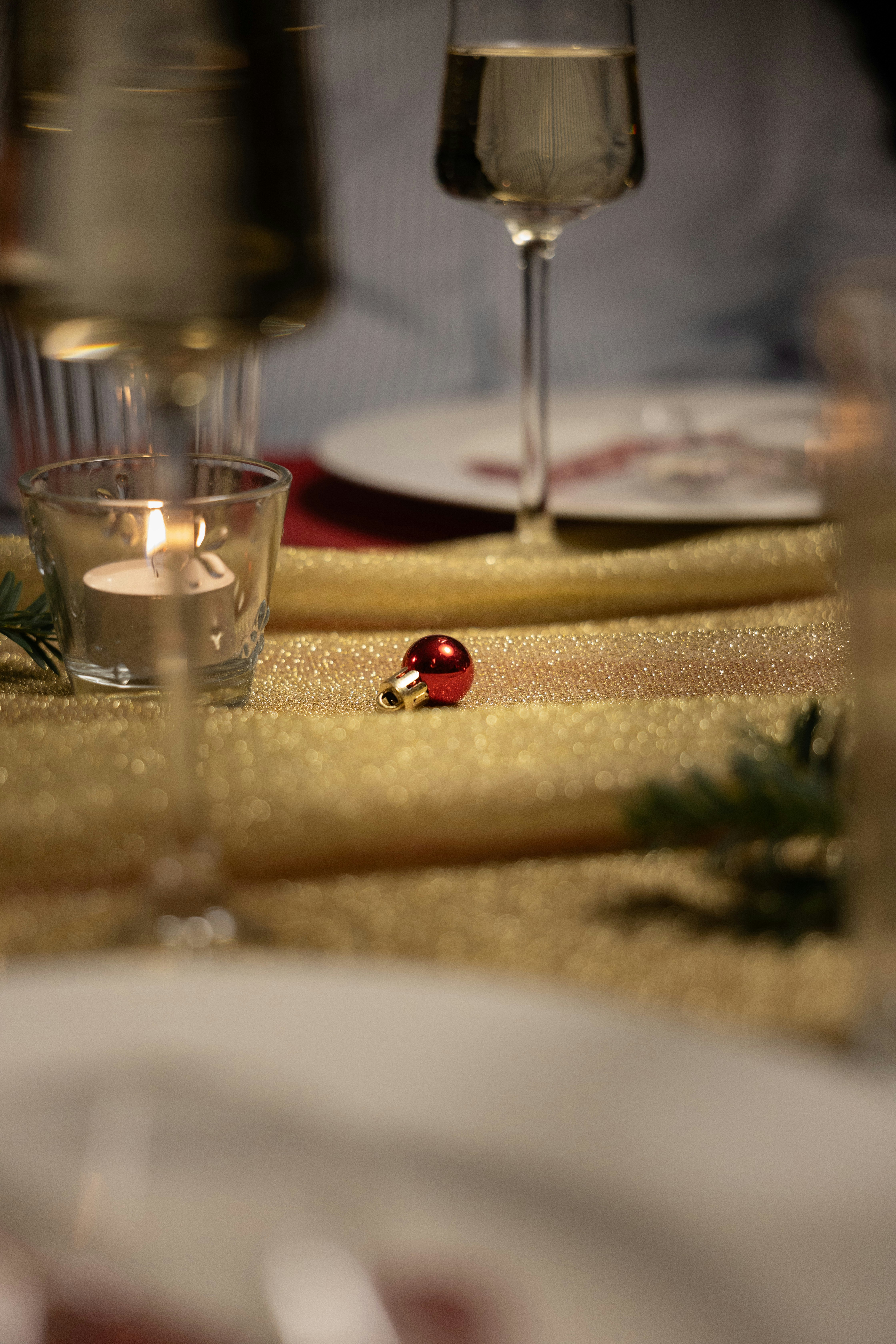 Ein kleines rotes Ornament auf einer glitzernden goldenen Tischdecke.