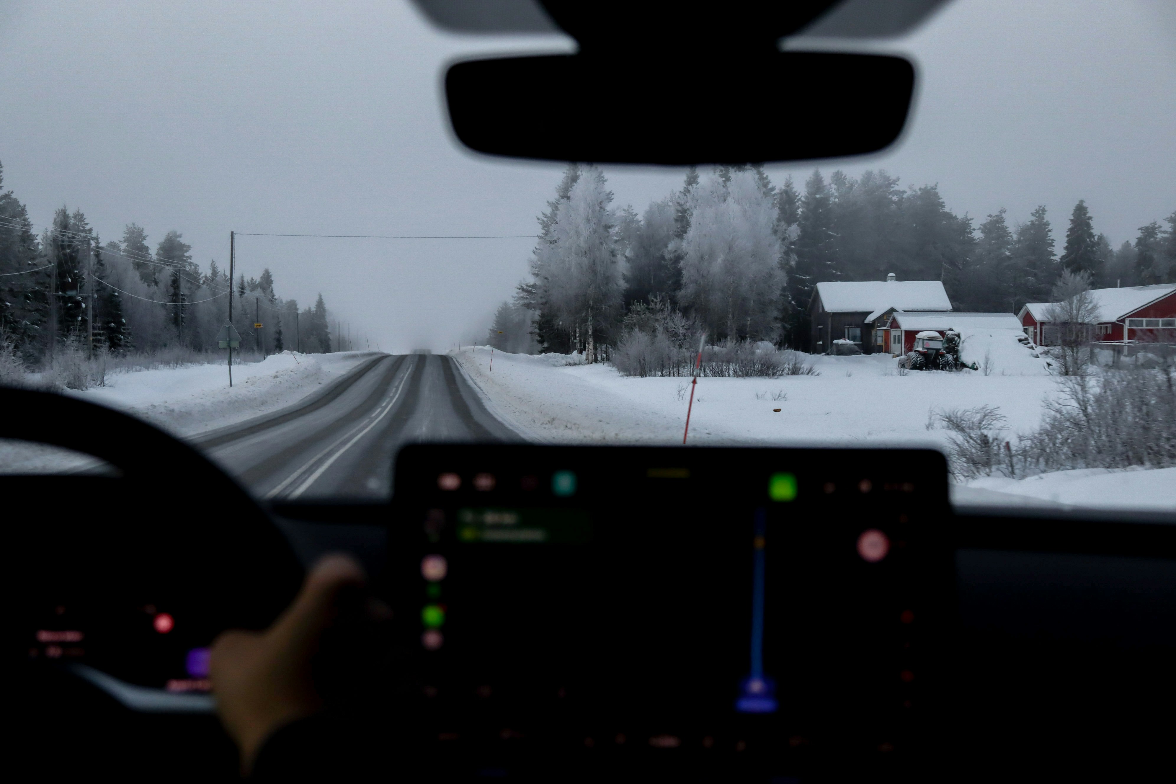 Driving on a snowy road through a winter forest