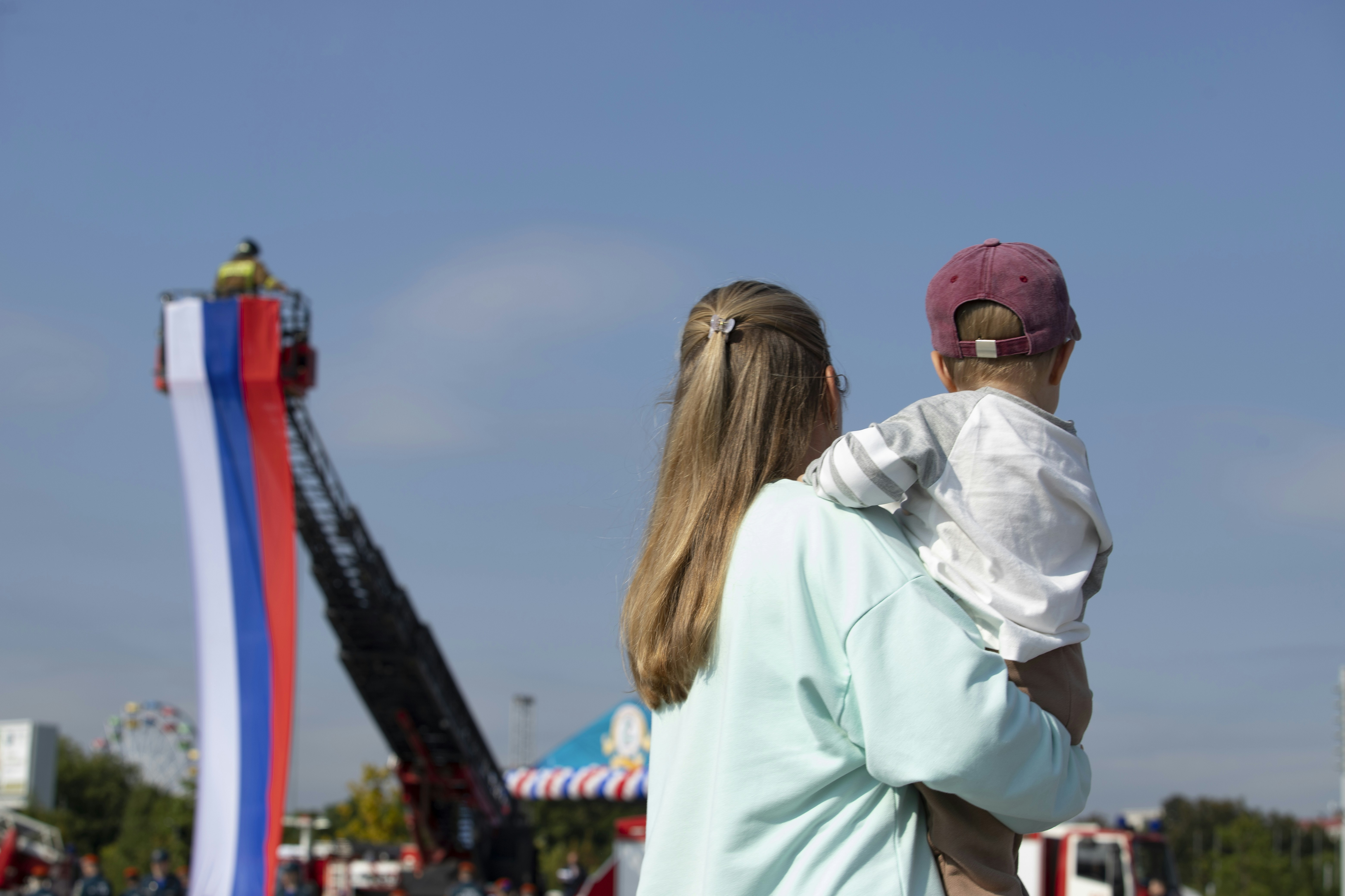 Woman holding a child at a carnival.