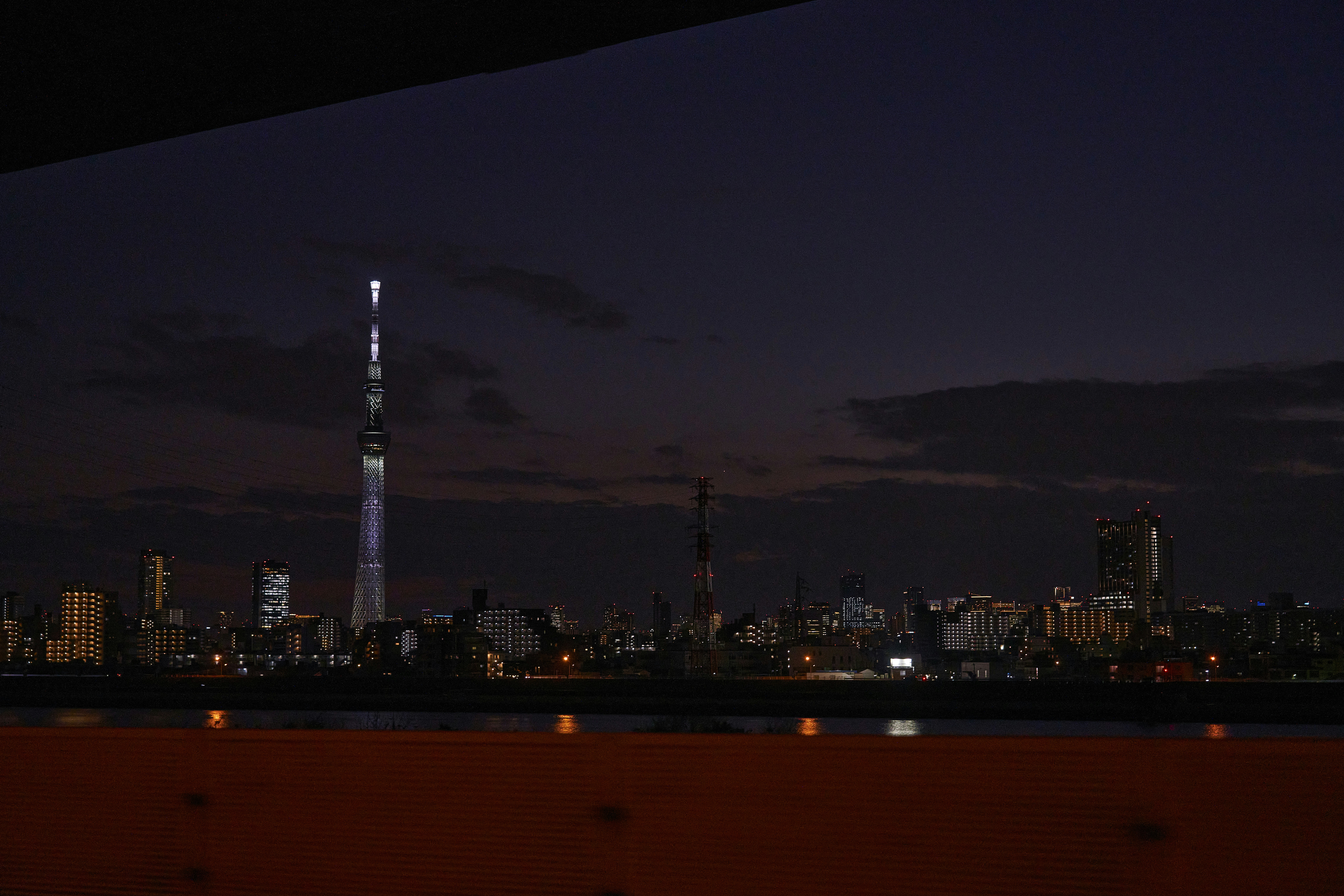 City skyline with tall illuminated tower at dusk