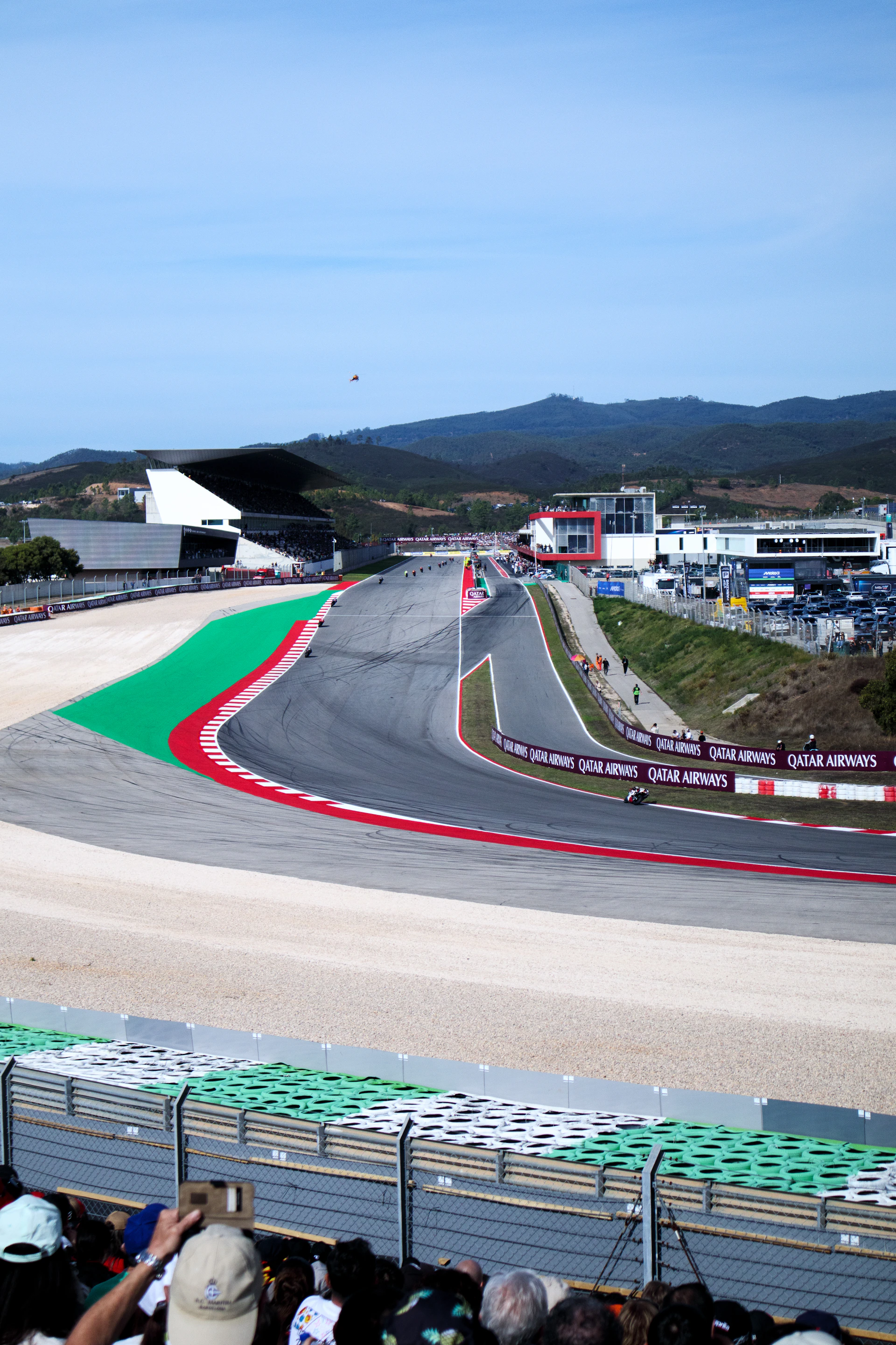 Race track with spectators and grandstands on a sunny day.