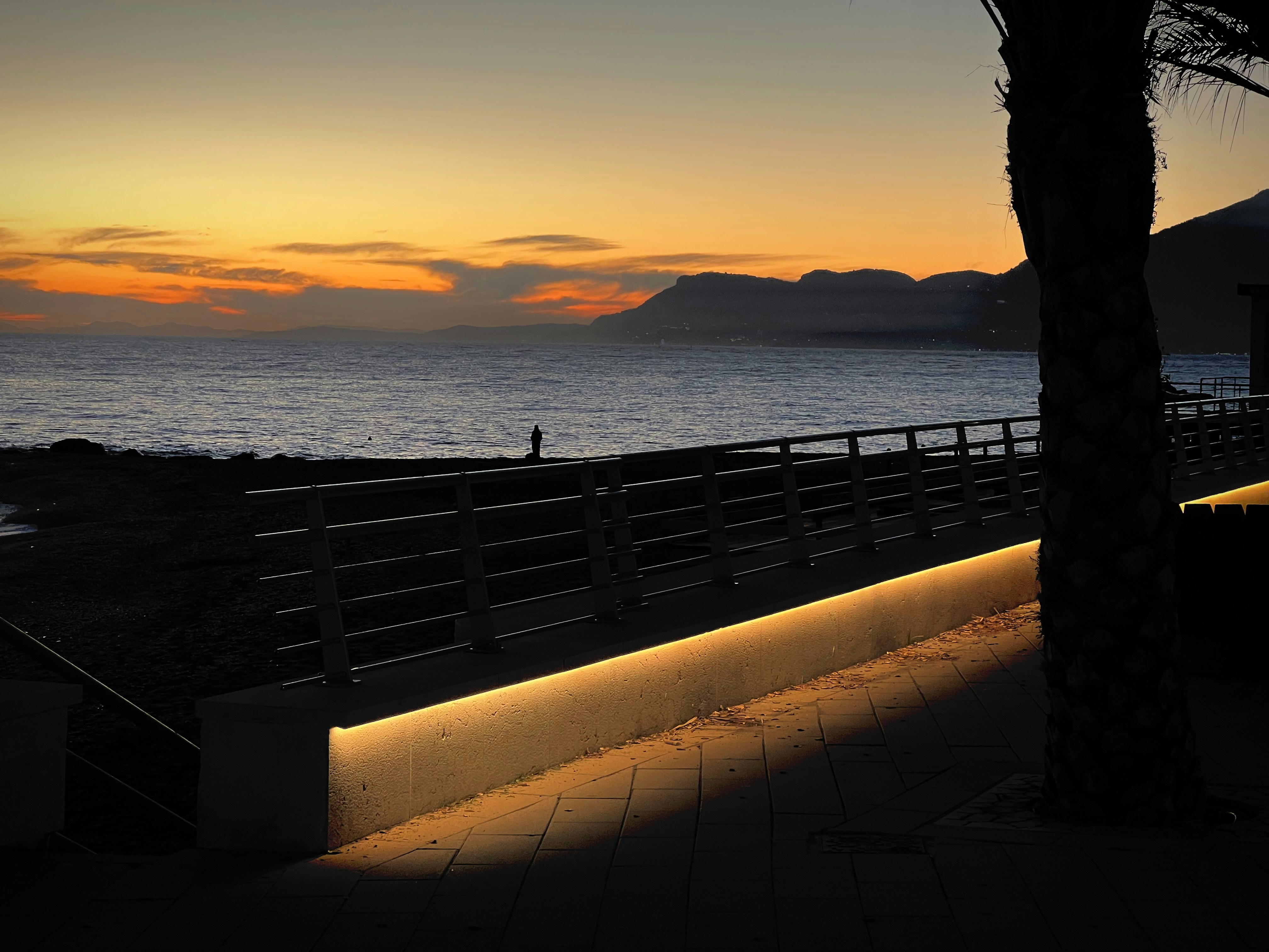 Sonnenuntergang über dem Ozean mit einem beleuchteten Steg