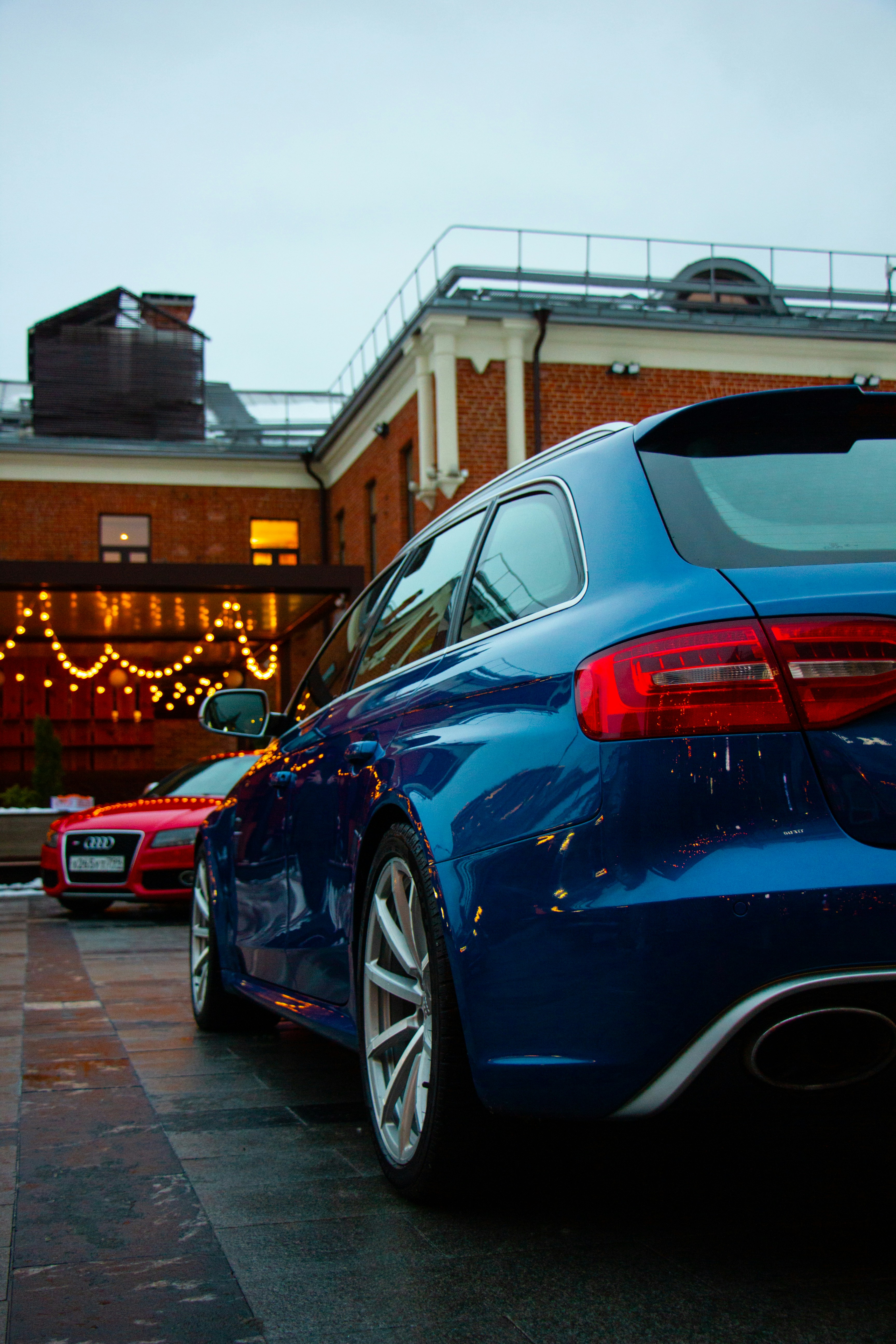 Two luxury cars parked outside a brick building