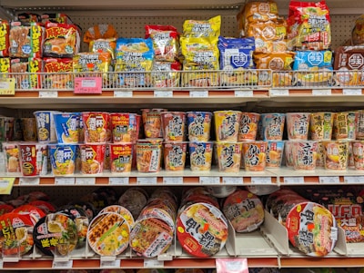 Shelves stocked with various instant noodle cups and snacks.