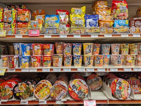 Shelves stocked with various instant noodle cups and snacks.