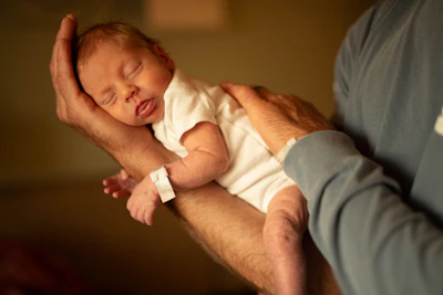 A newborn baby sleeping peacefully in a person's arms.