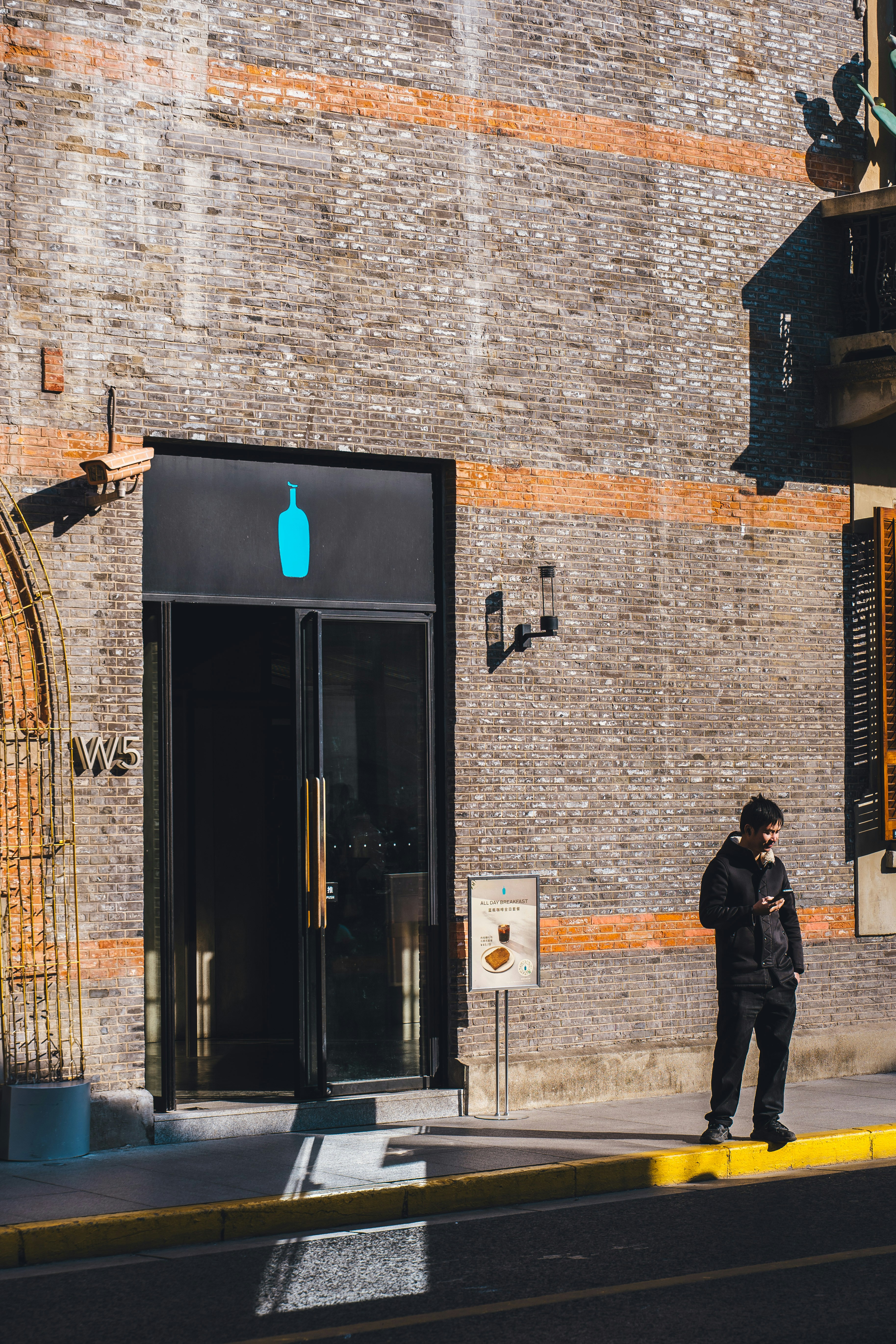 Man standing outside building with blue bottle logo