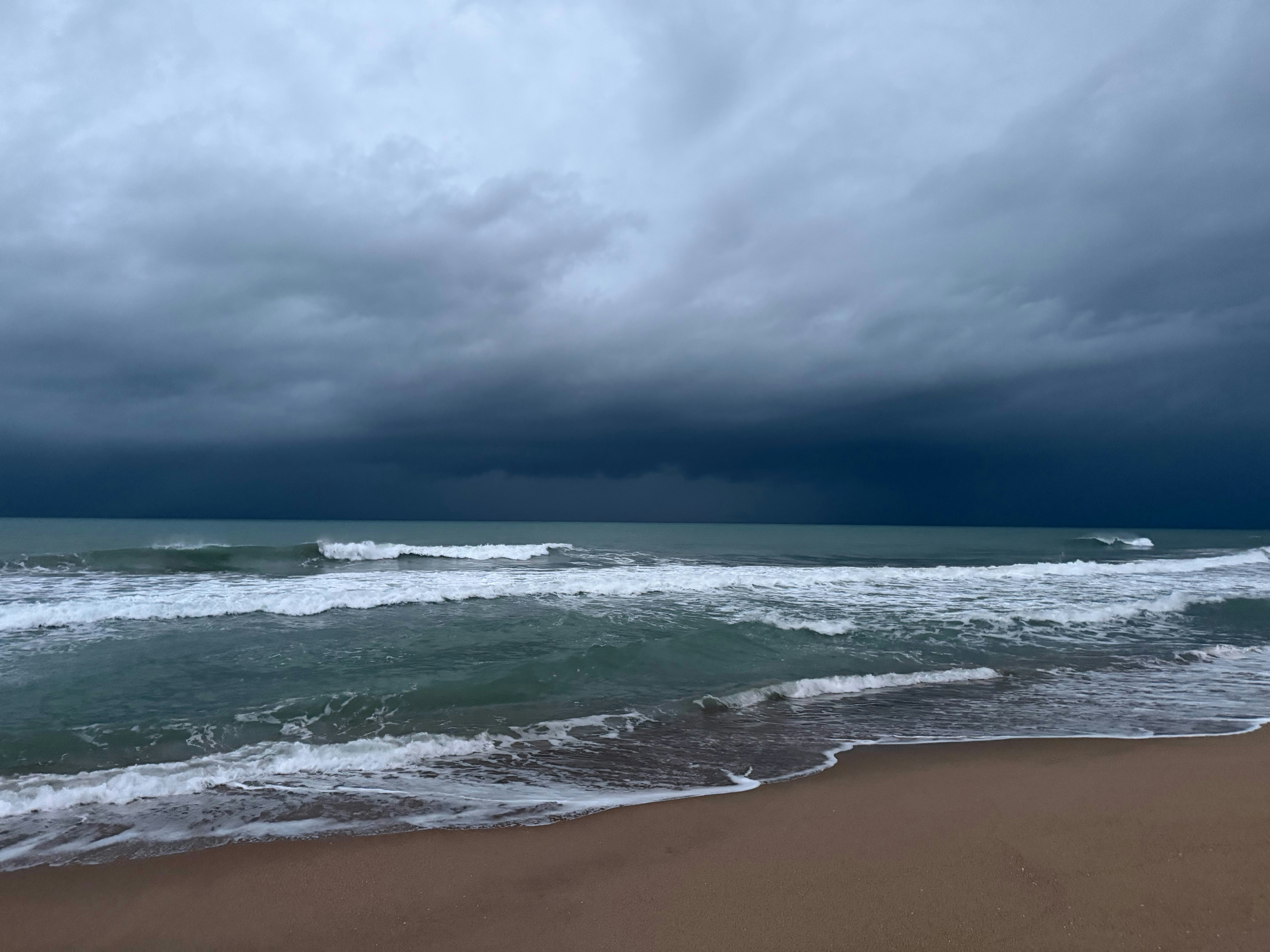 Dark storm clouds gather over the ocean waves.
