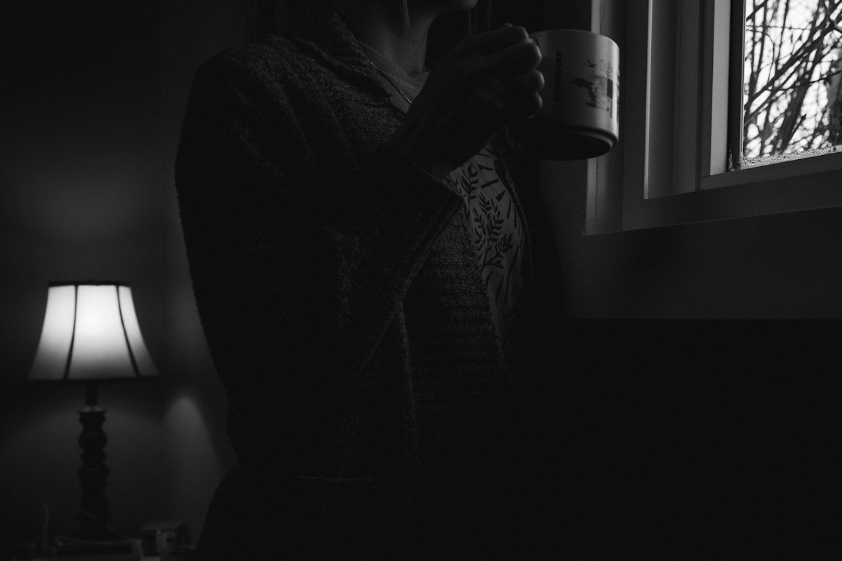 Personne tenant une tasse près d'une fenêtre, moment de calme