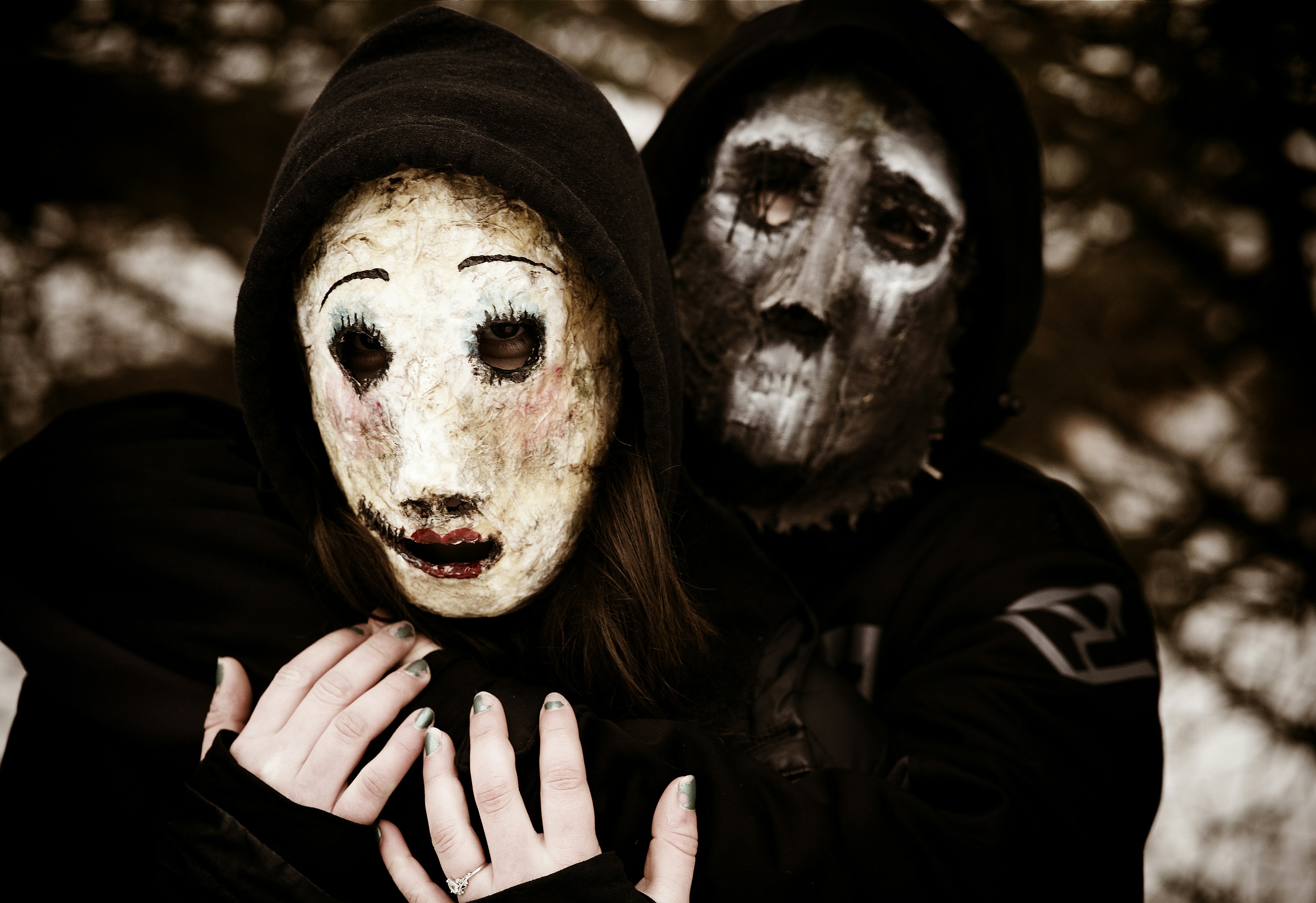 Two people wearing creepy masks and hoods