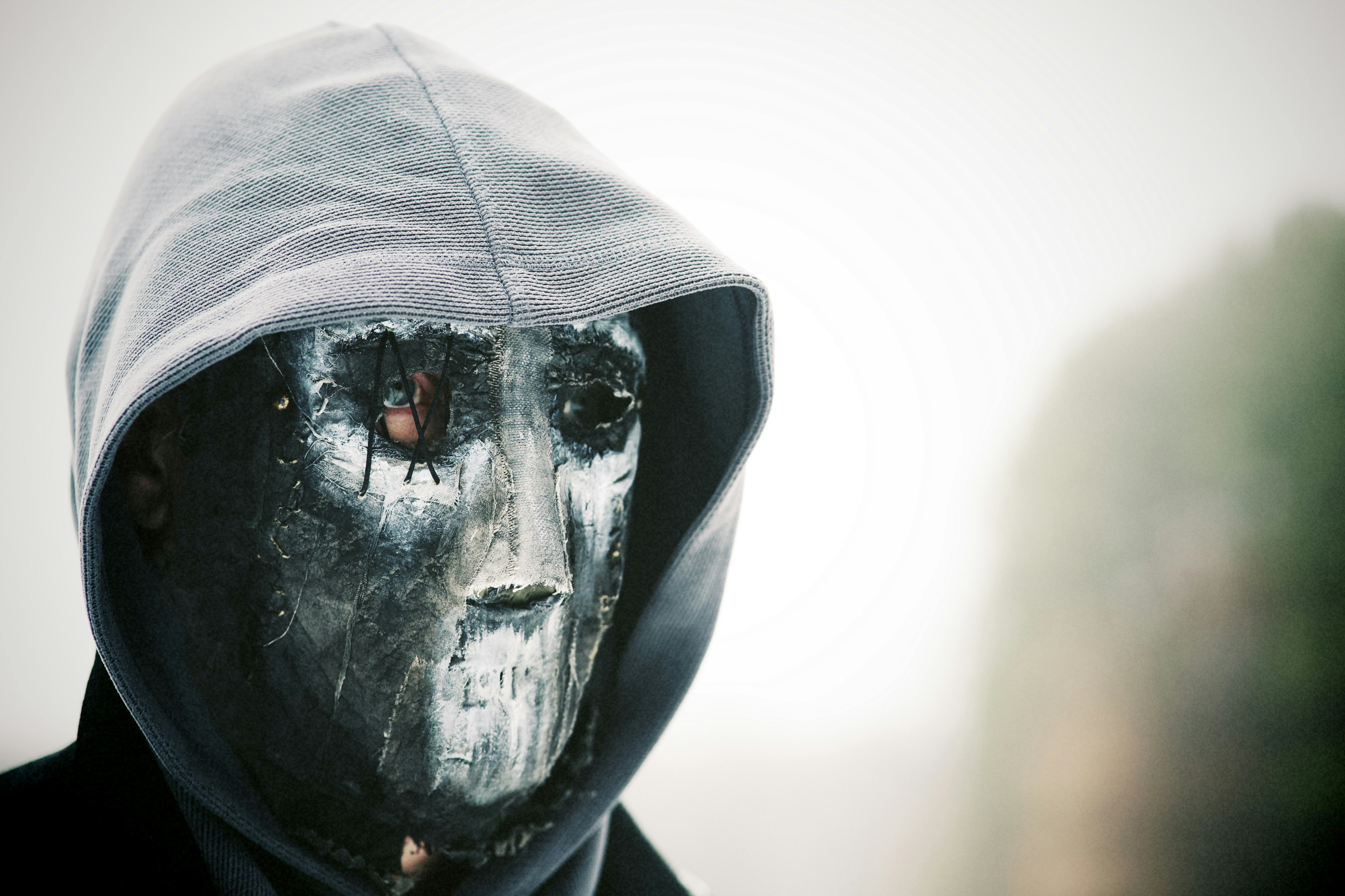Person wearing a mask and hoodie outdoors
