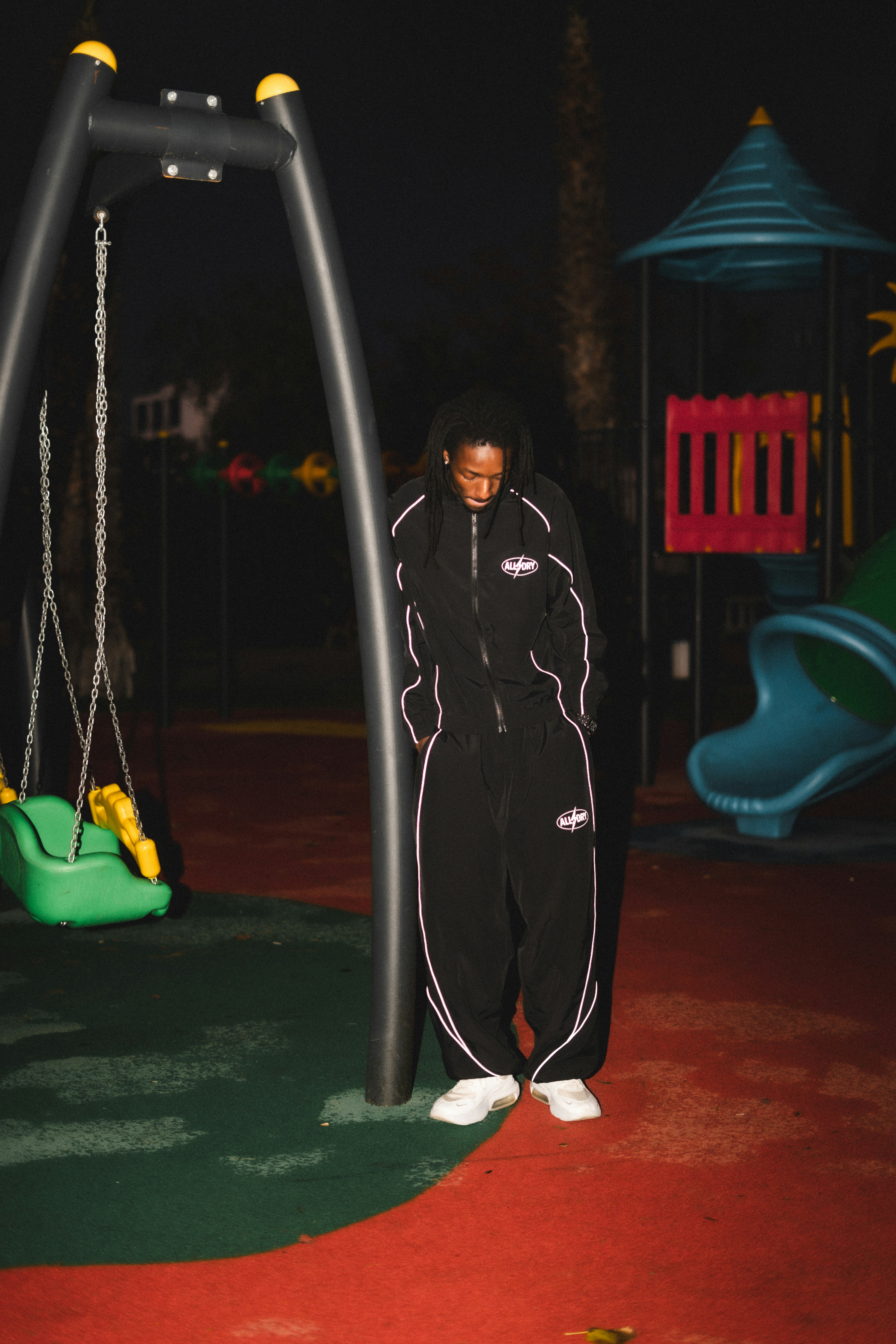 Person in tracksuit at a playground at night playground