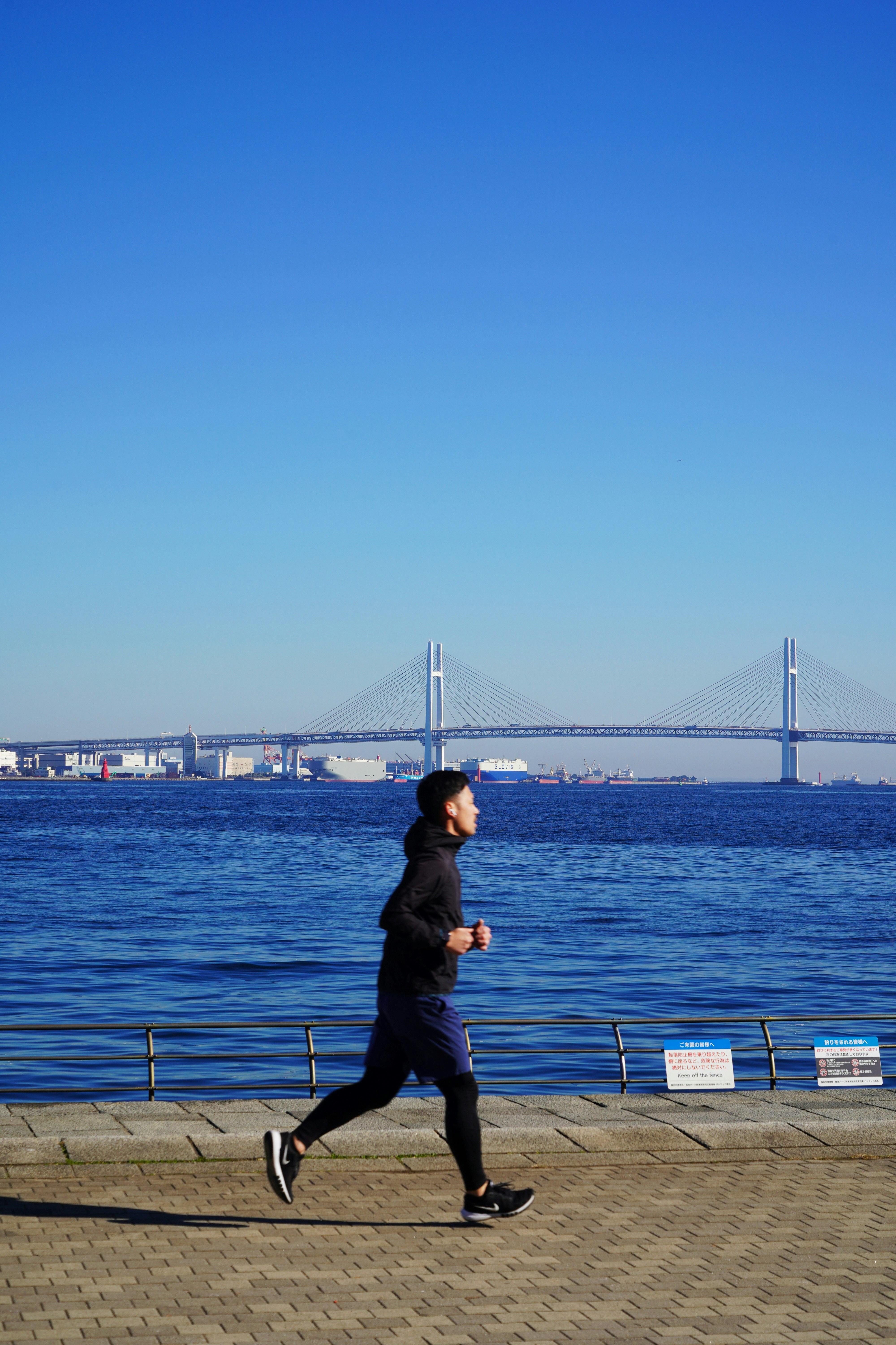 Man running by the ocean with bridge background