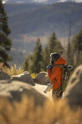 Hiker with camera and backpack in mountains.