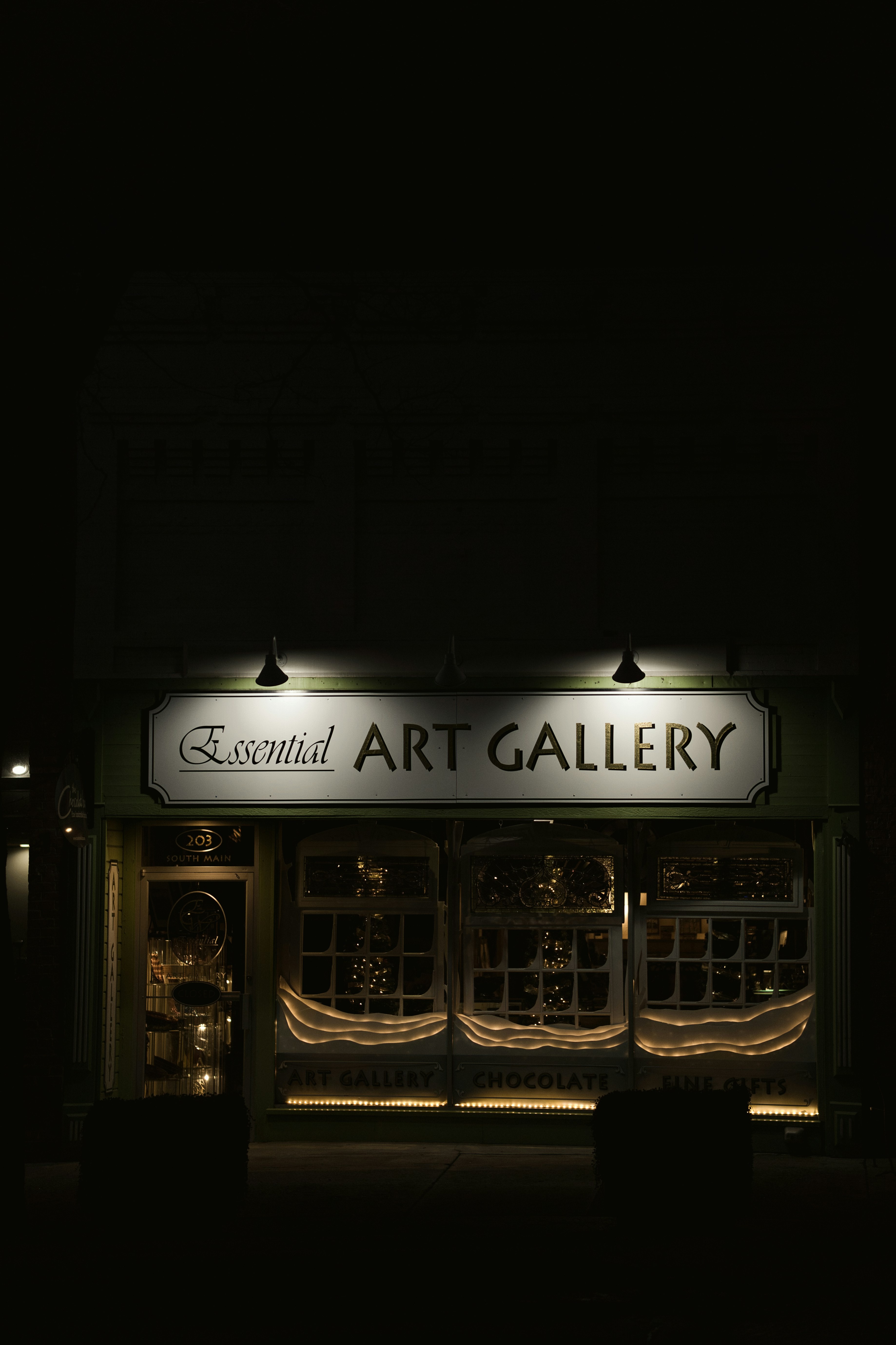 Essential art gallery storefront at night
