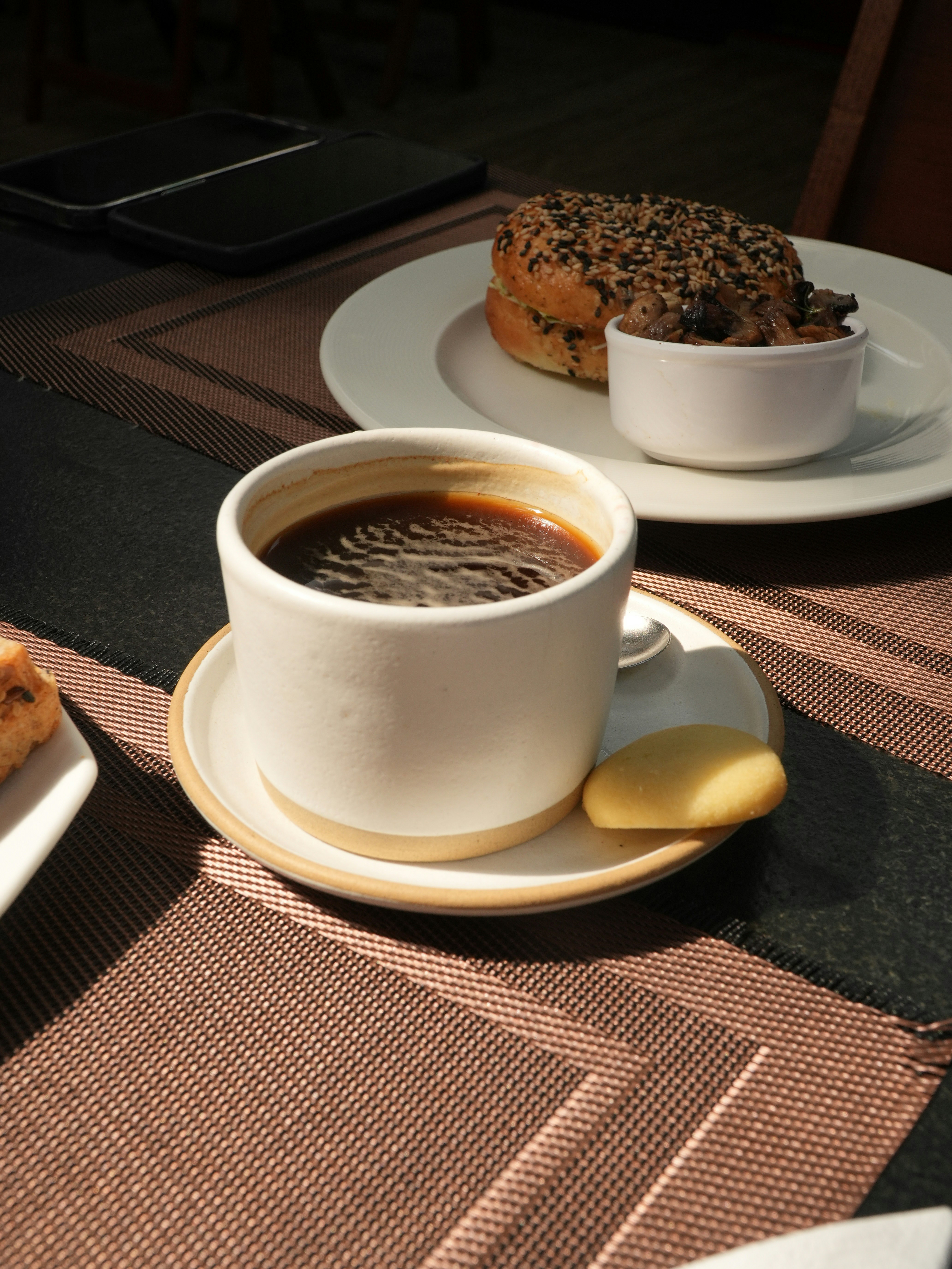 A cup of coffee with a cookie and pastry.