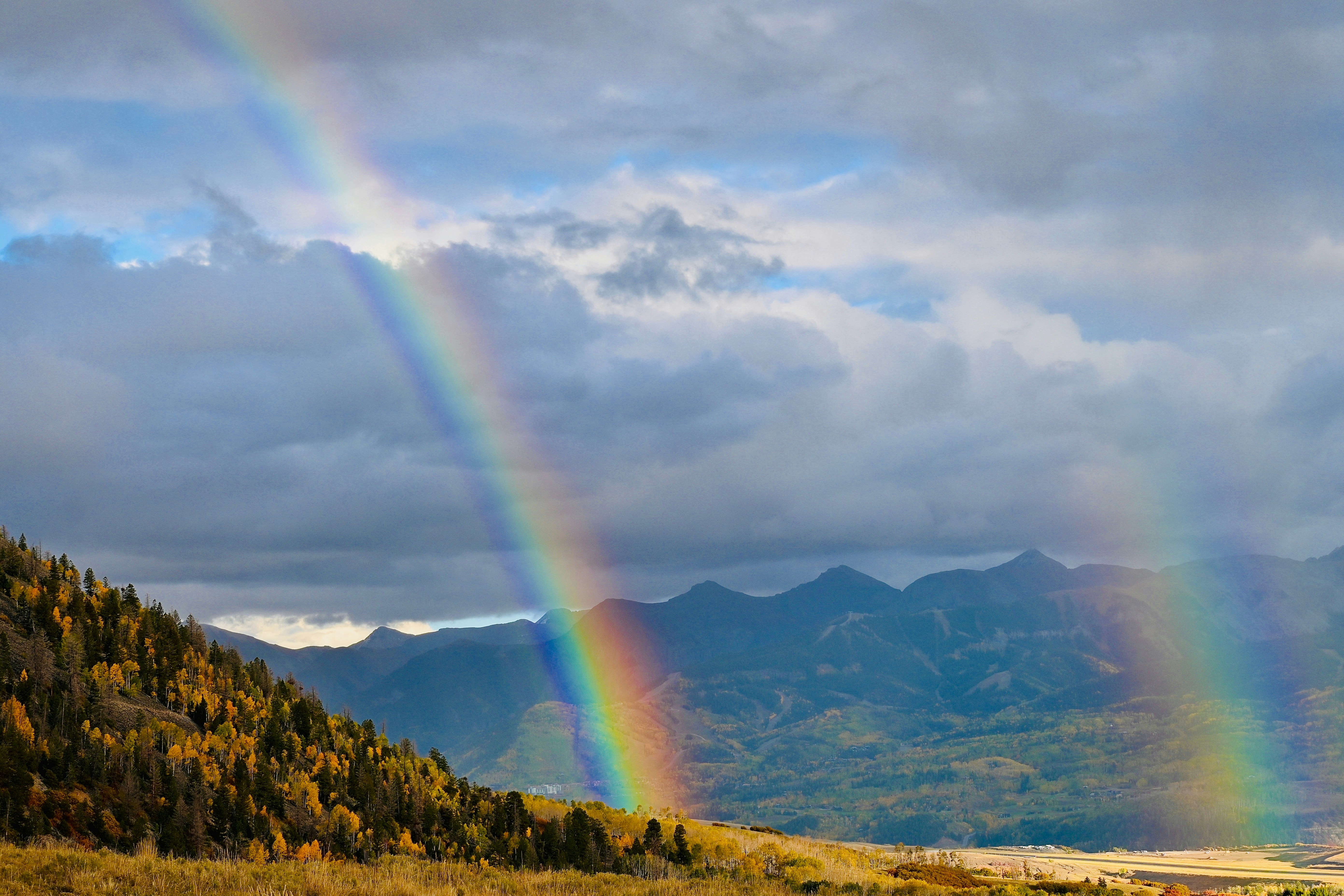 Rainbow over autumn mountains with dramatic clouds