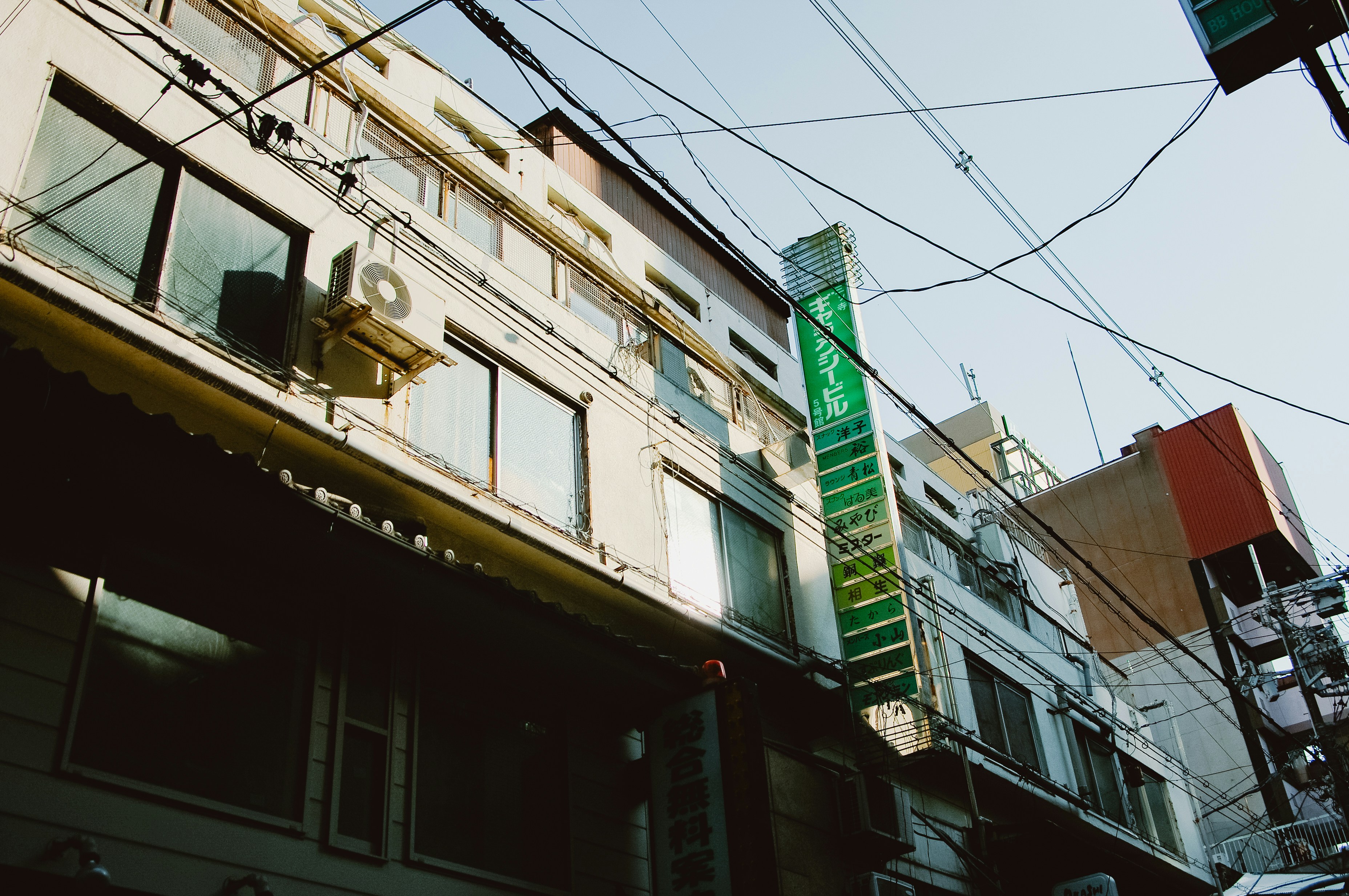 Buildings with a green sign and wires above
