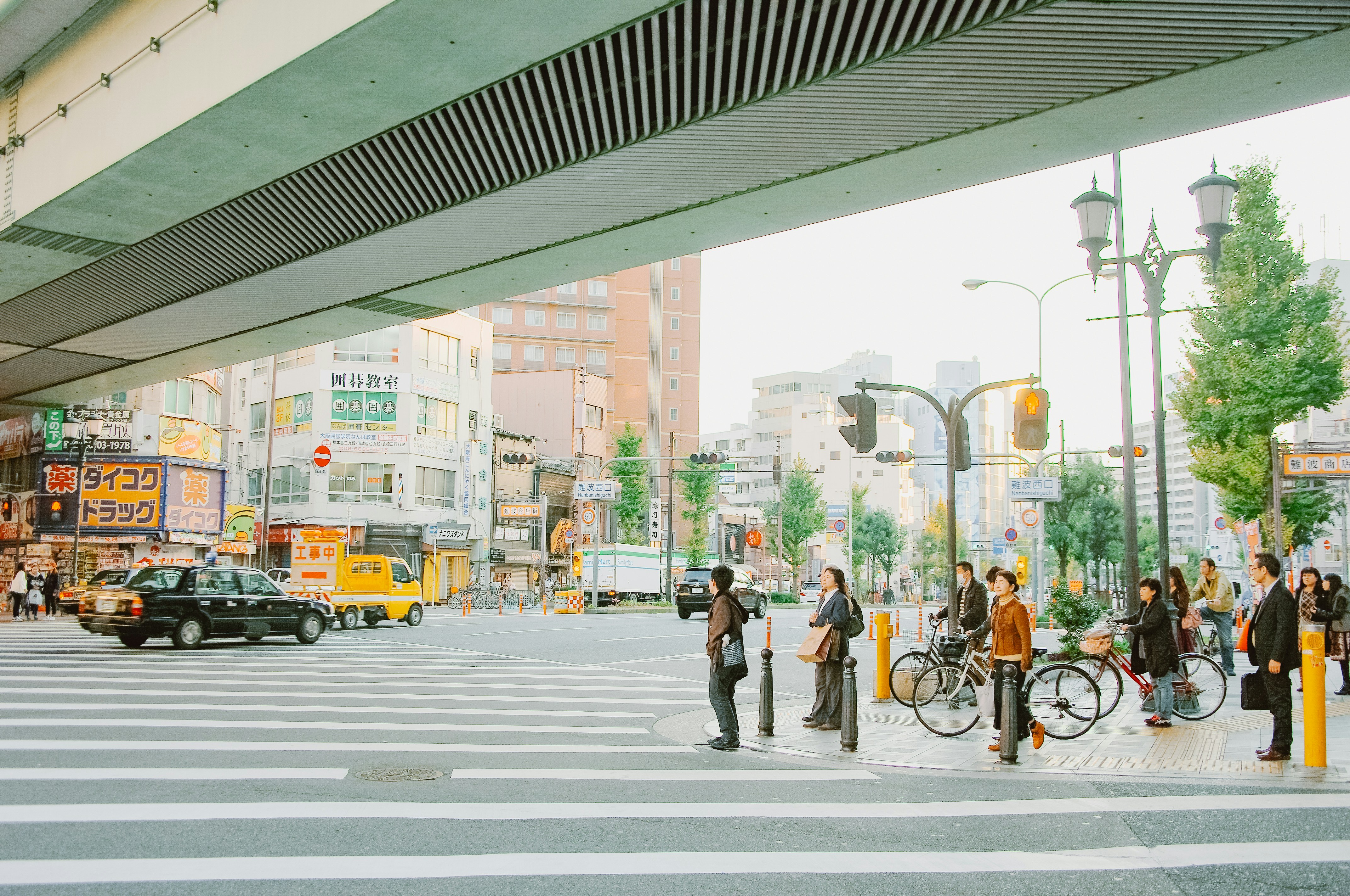 People crossing street under overpass in city