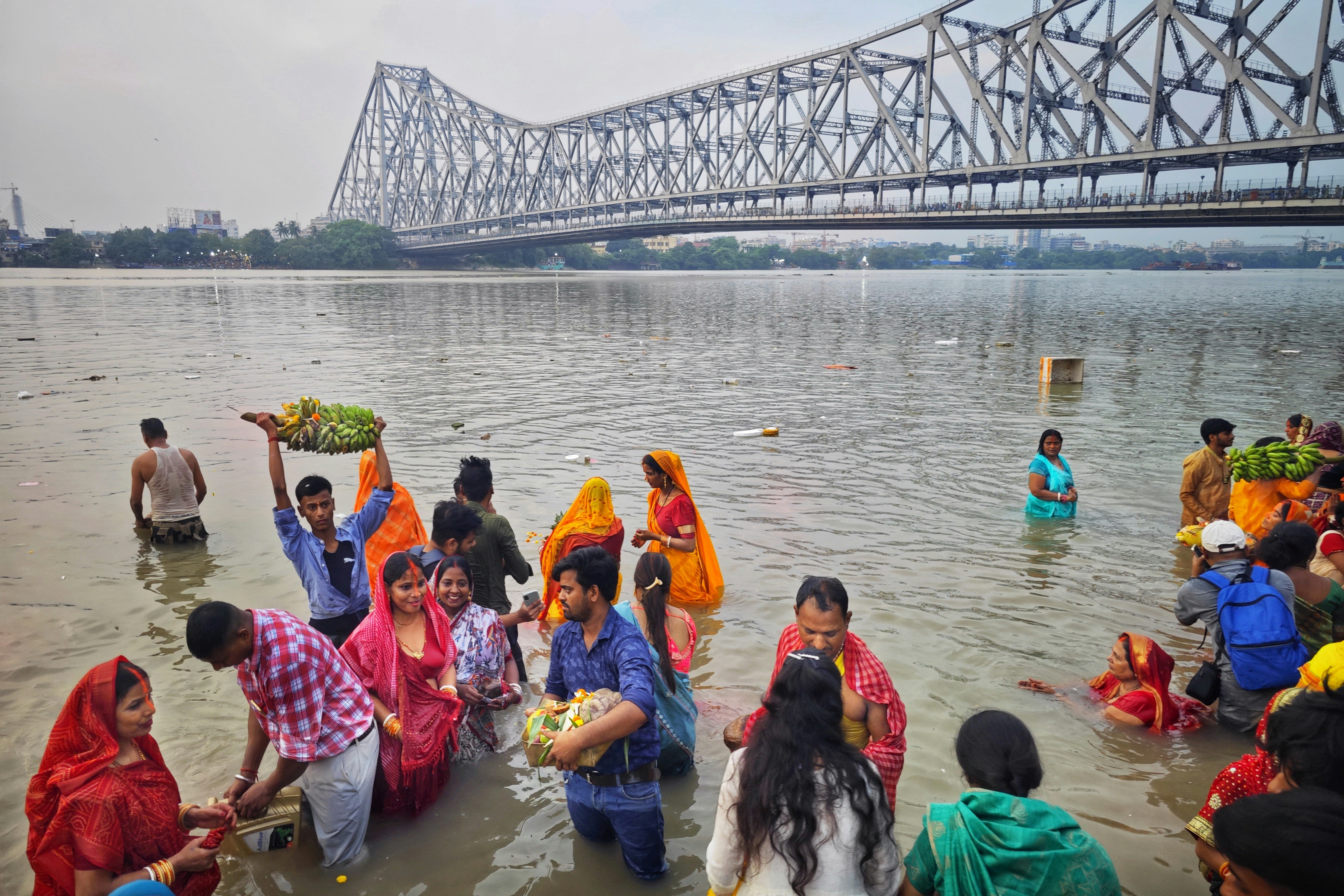 People bathing in a river with a bridge overhead