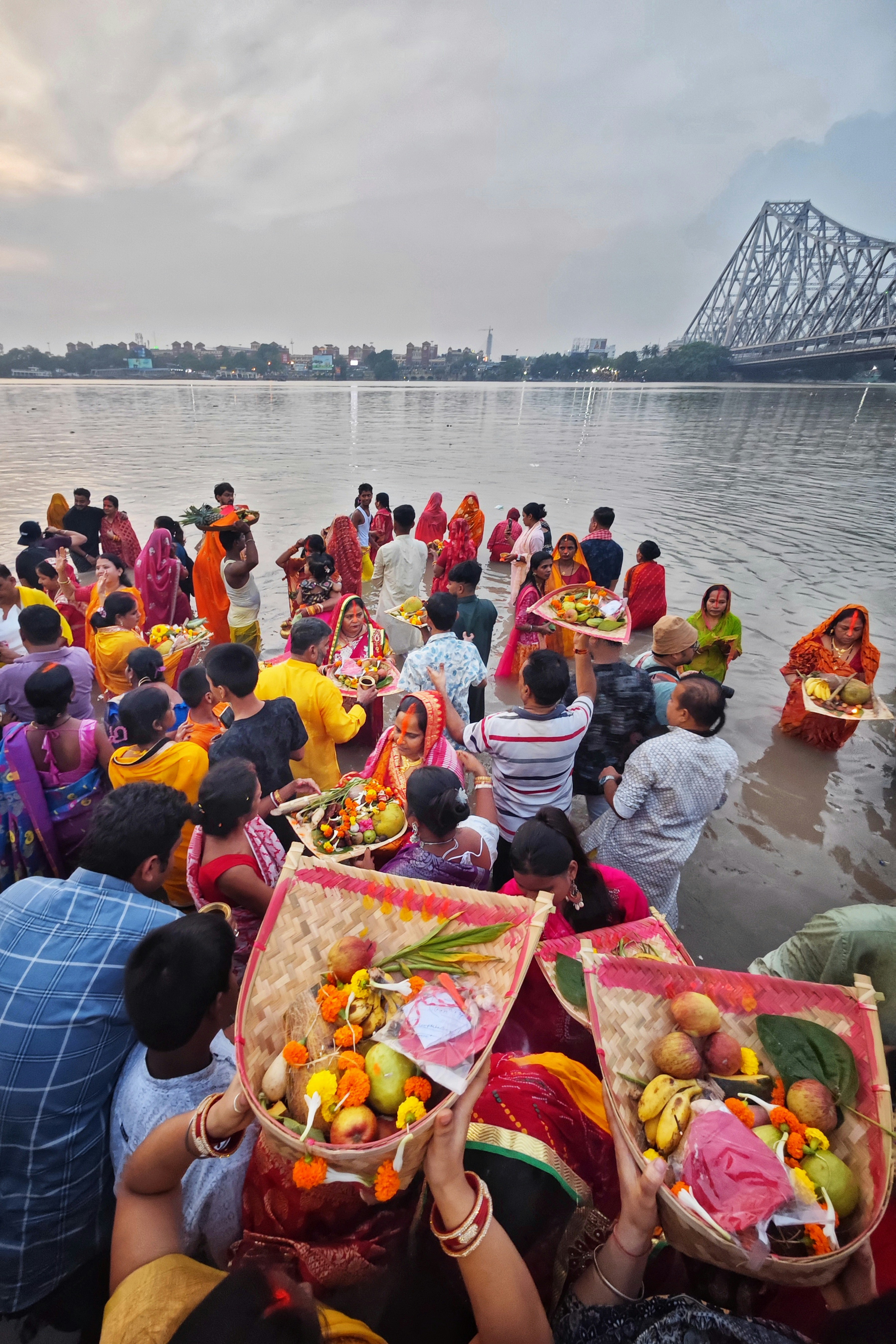 People gathered by a river with offerings