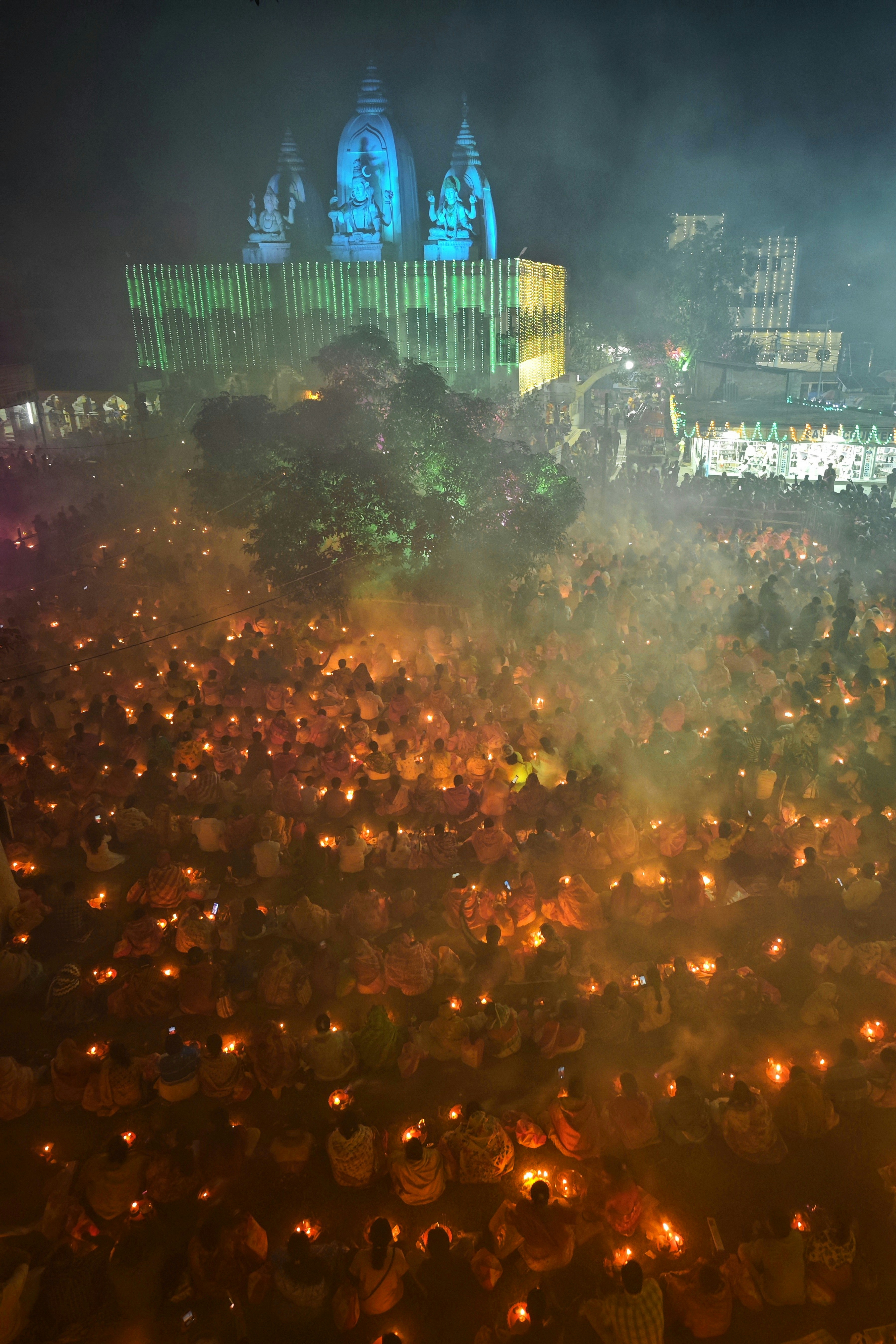 Crowd holding candles at a illuminated temple at night